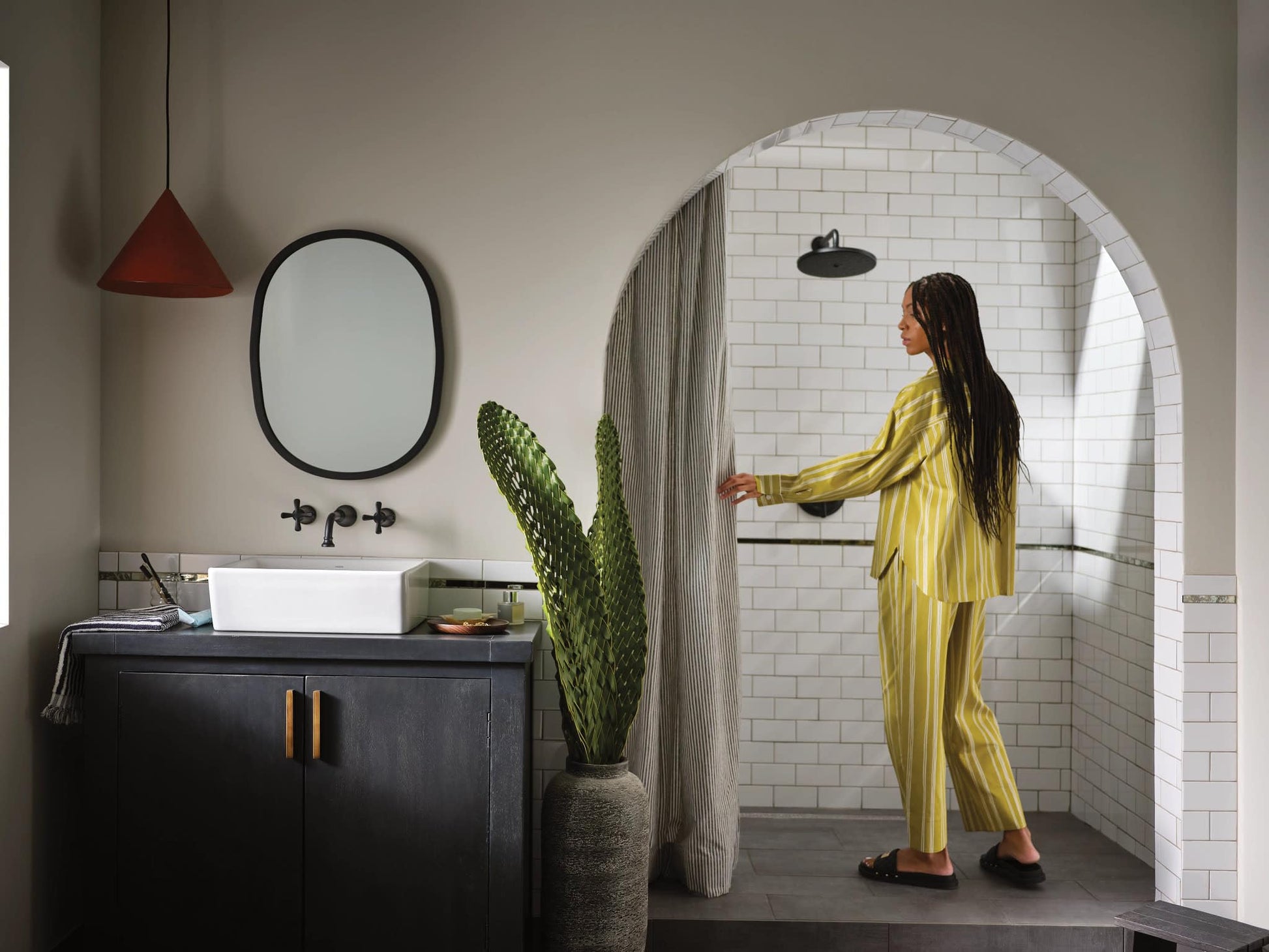 Matte black wall-mounted bathroom faucet with cross handles and spout above white vessel sink.