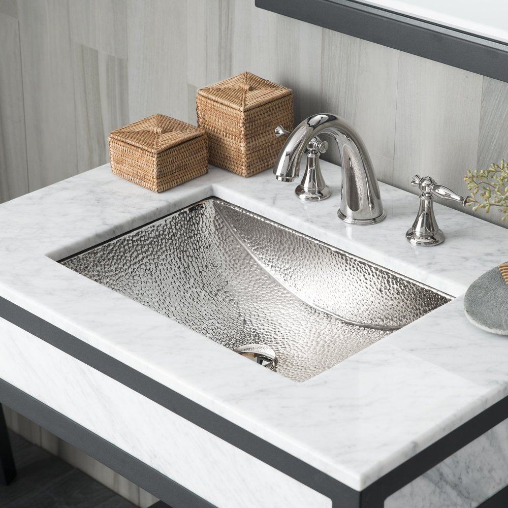 Polished nickel undermount sink with hammered texture and matching three-hole faucet set on marble countertop.