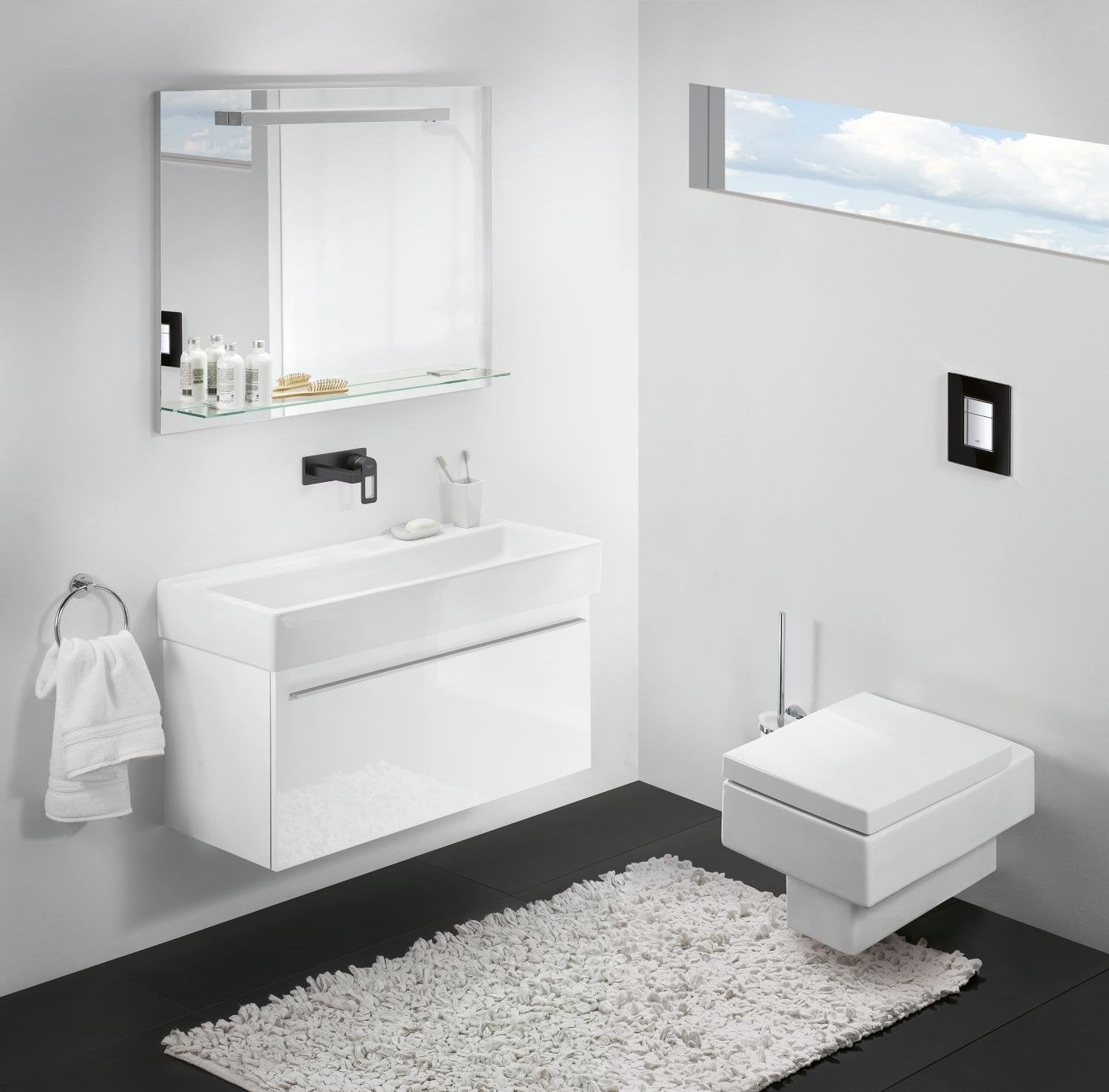 Black square wall plate mounted on bathroom wall next to toilet and sink fixture.