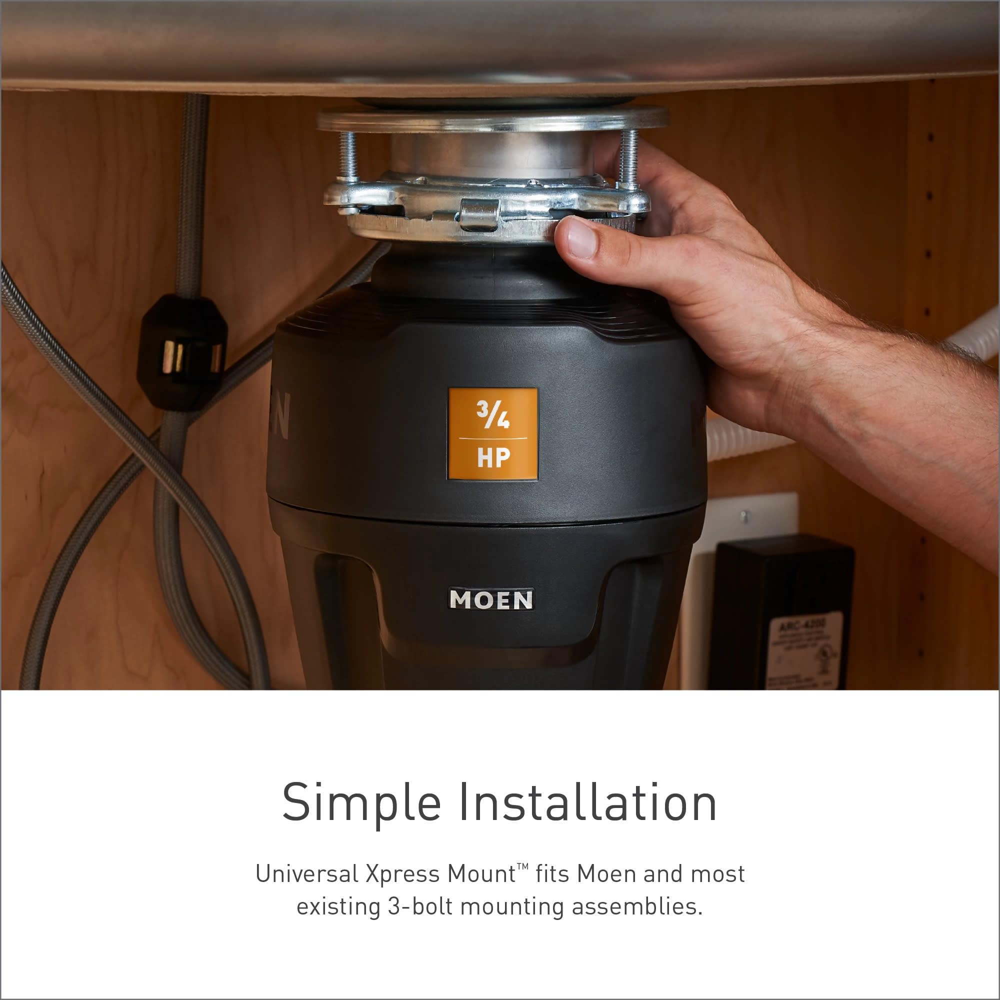 Black Moen garbage disposal with 3/4 HP label installed under sink cabinet with mounting hardware visible.