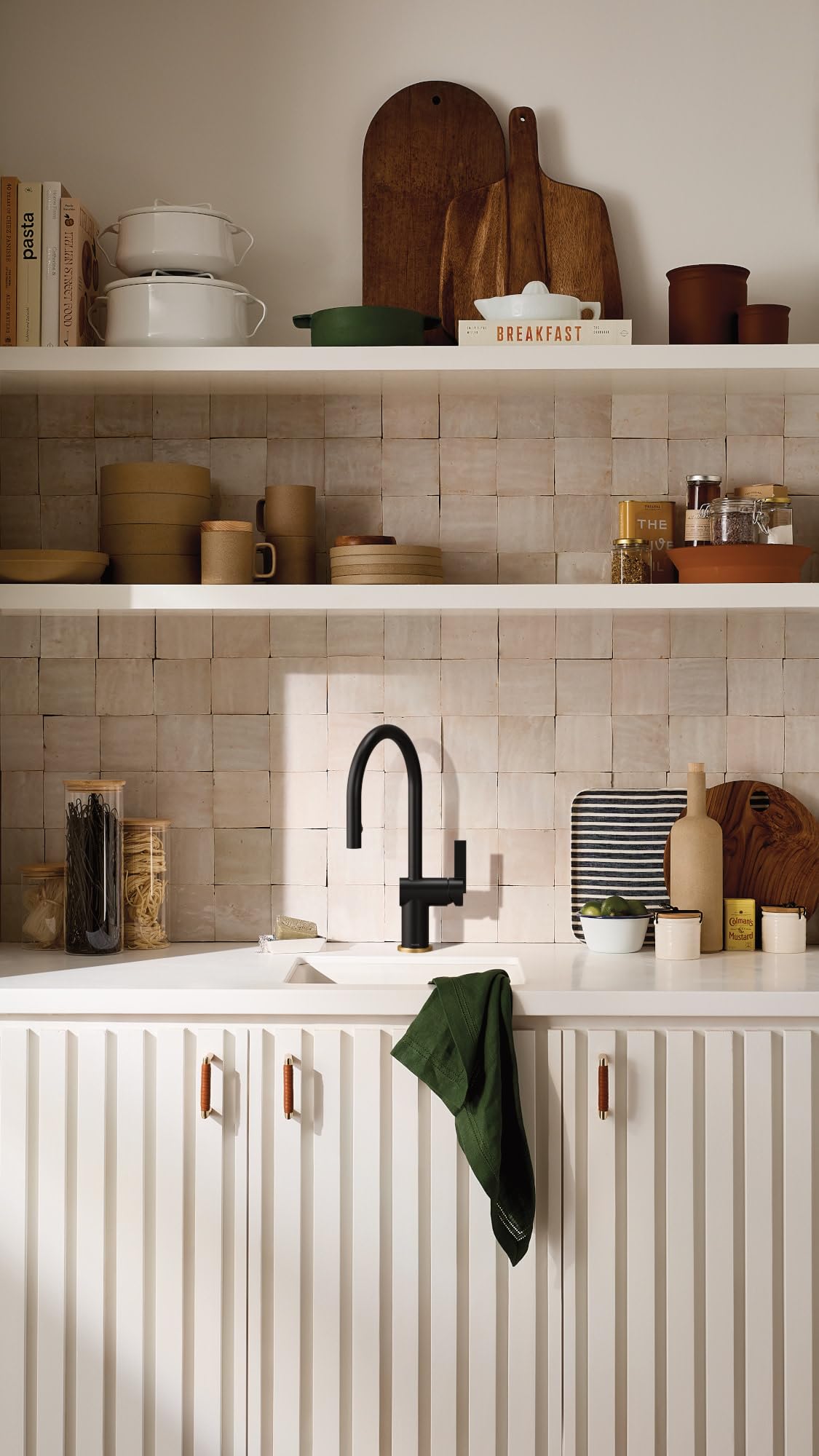 Matte black pulldown kitchen faucet with curved spout installed above white sink in tiled kitchen.