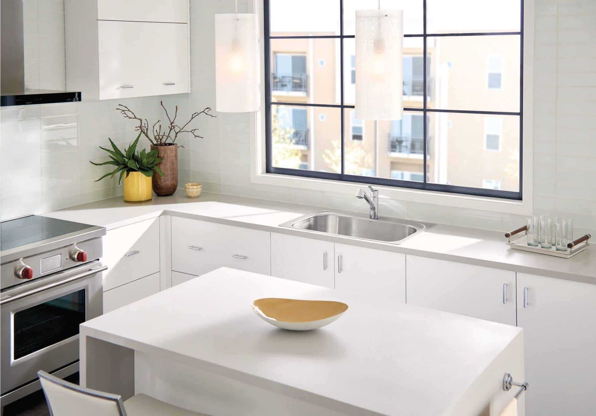 Stainless steel single-handle kitchen faucet with pullout sprayer installed in white sink, shown in modern kitchen setting.