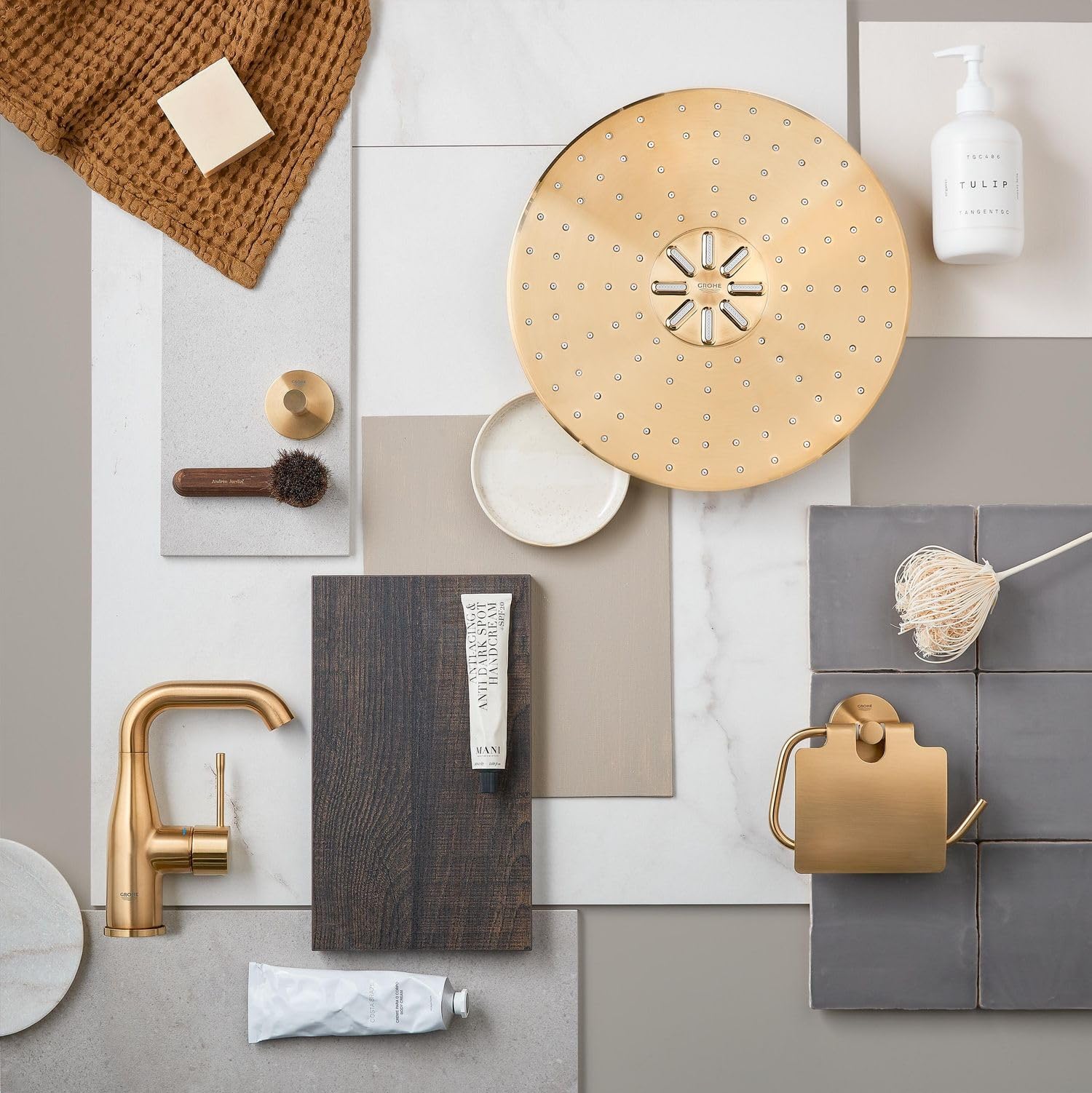 Brushed gold robe hook with rounded handle mounted on gray tile wall in bathroom setting.