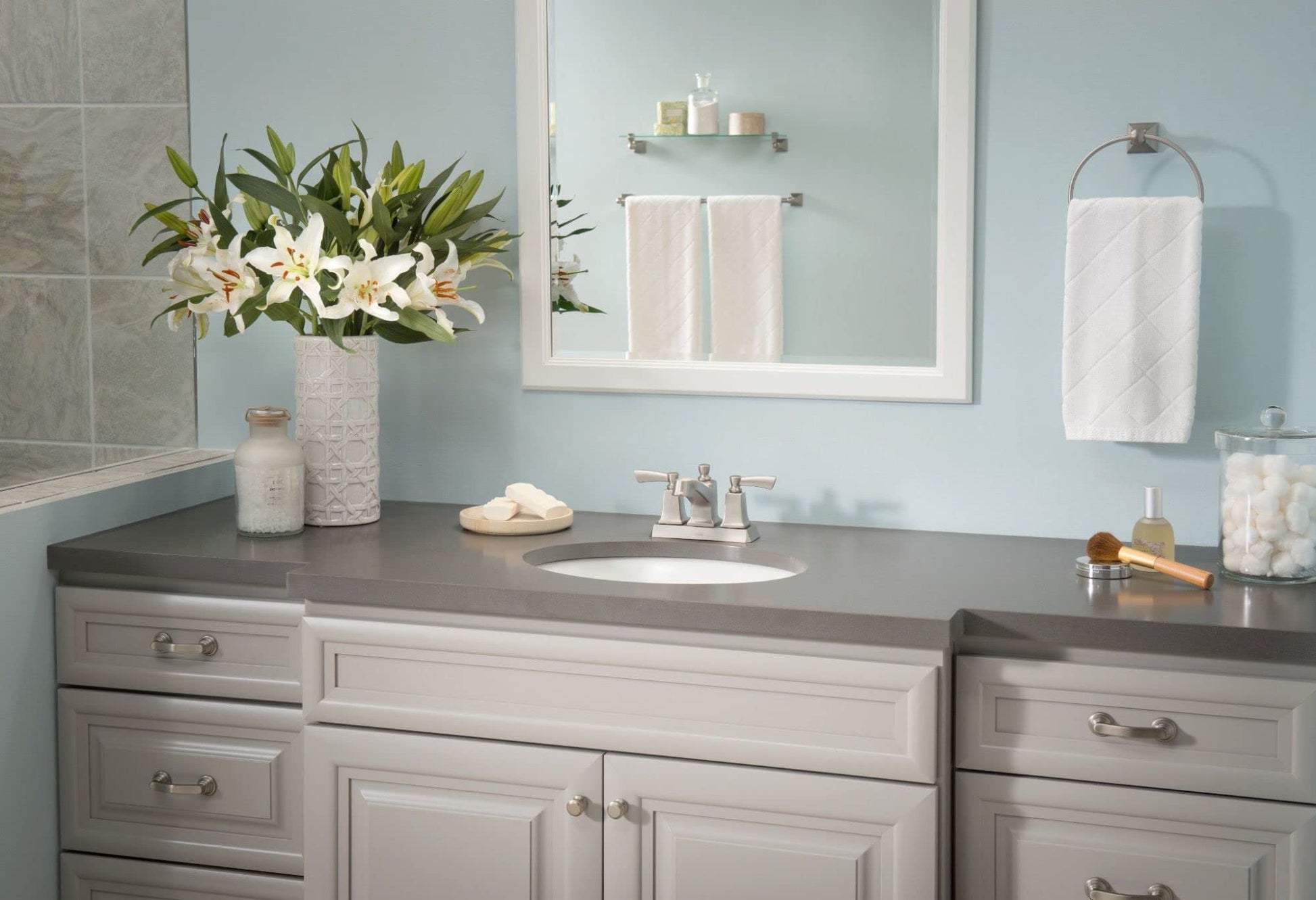 Brushed nickel wall-mounted towel ring holding a white hand towel in a bathroom setting.