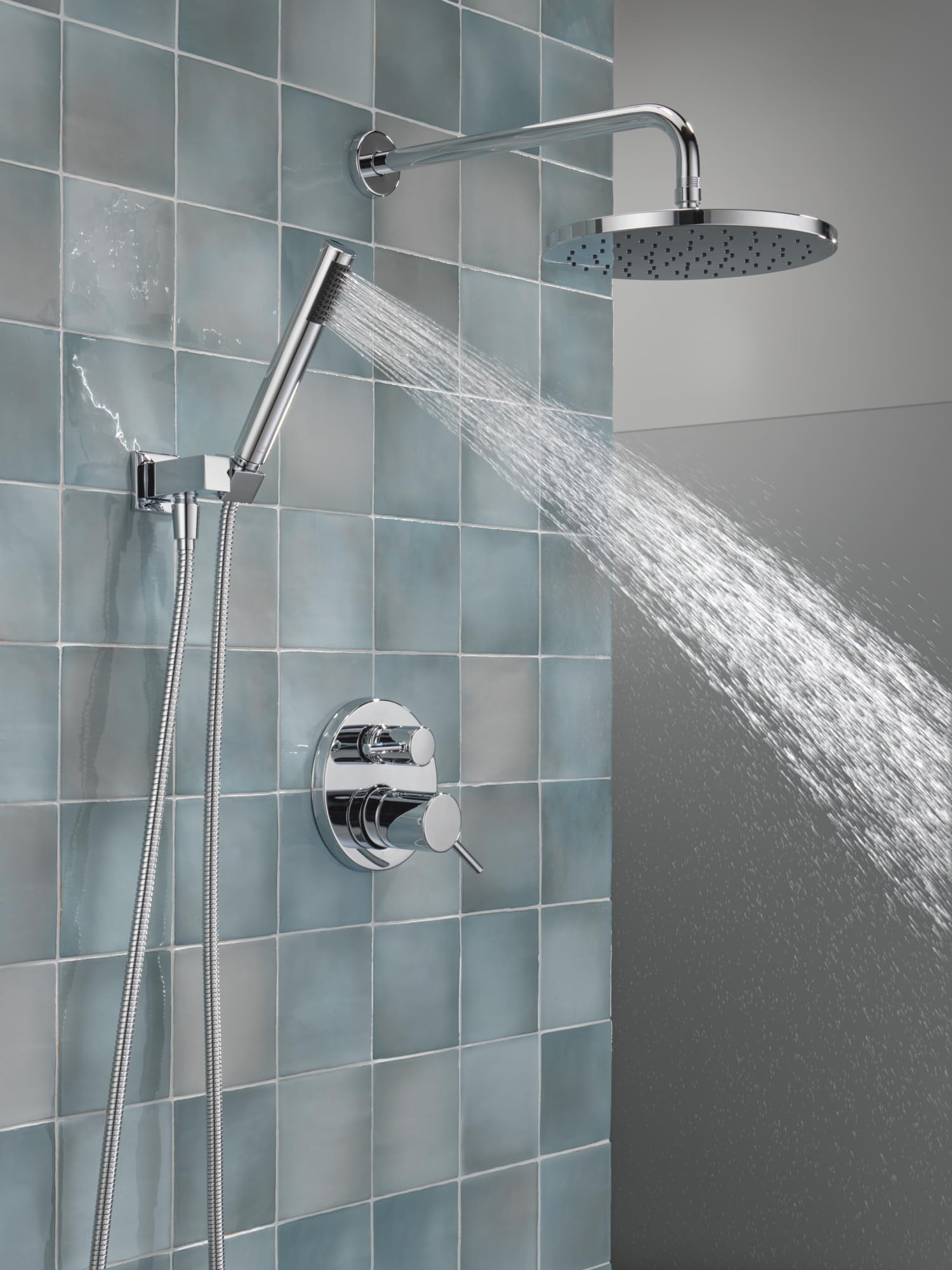 Chrome shower system with round raincan showerhead, handheld shower wand, and wall-mounted valve control on tiled bathroom wa