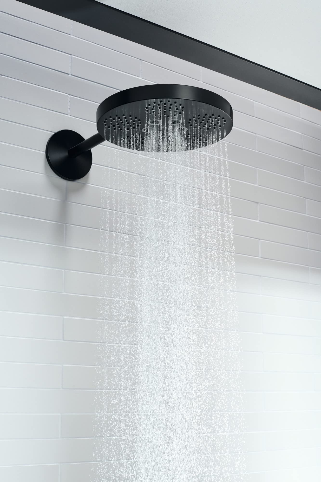 Matte black round shower head with 2-jet spray pattern mounted on white subway tile wall with curved arm trim.