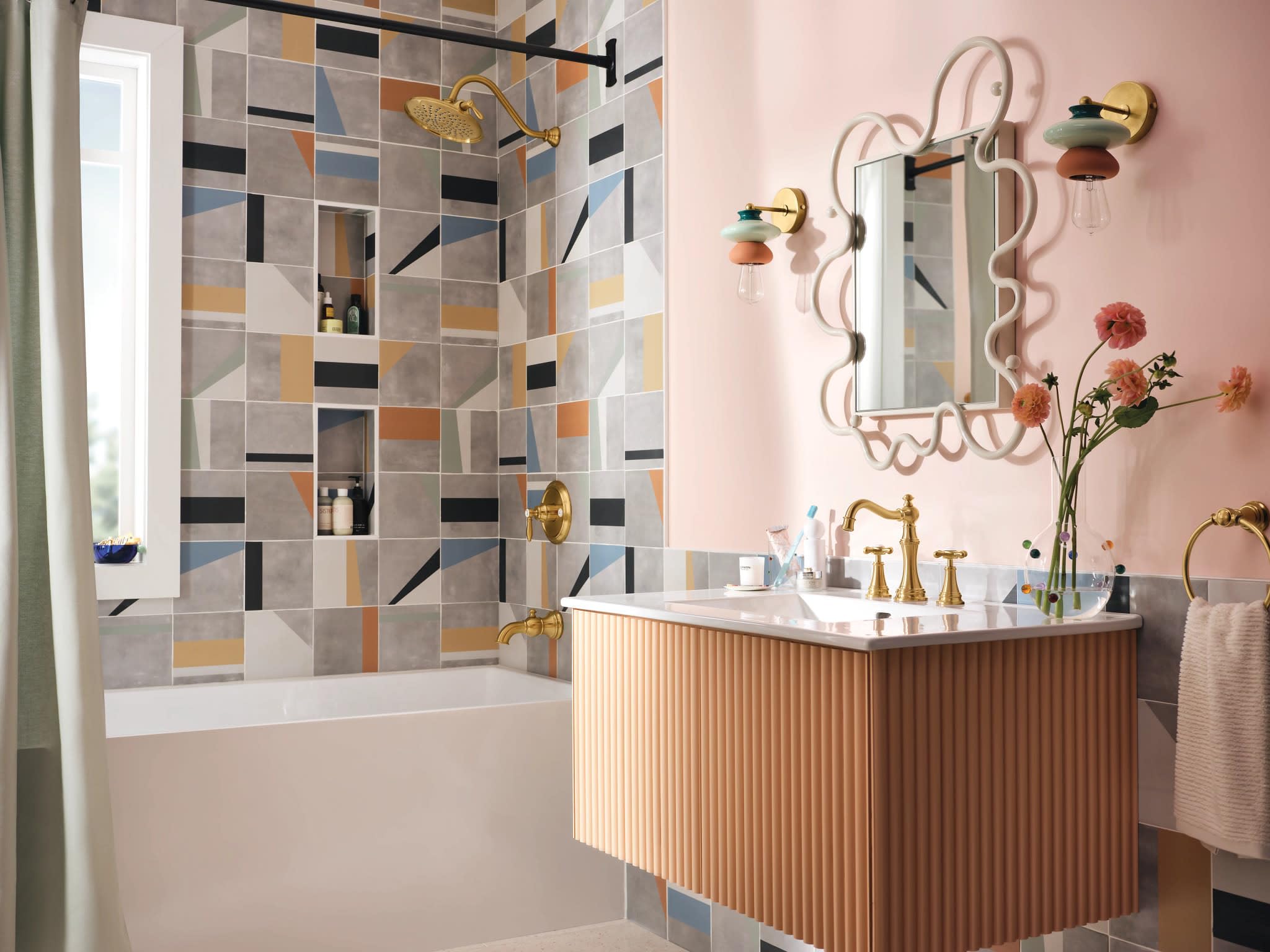 Brushed gold single-handle tub and shower trim kit mounted on colorful tile wall with matching showerhead and controls.