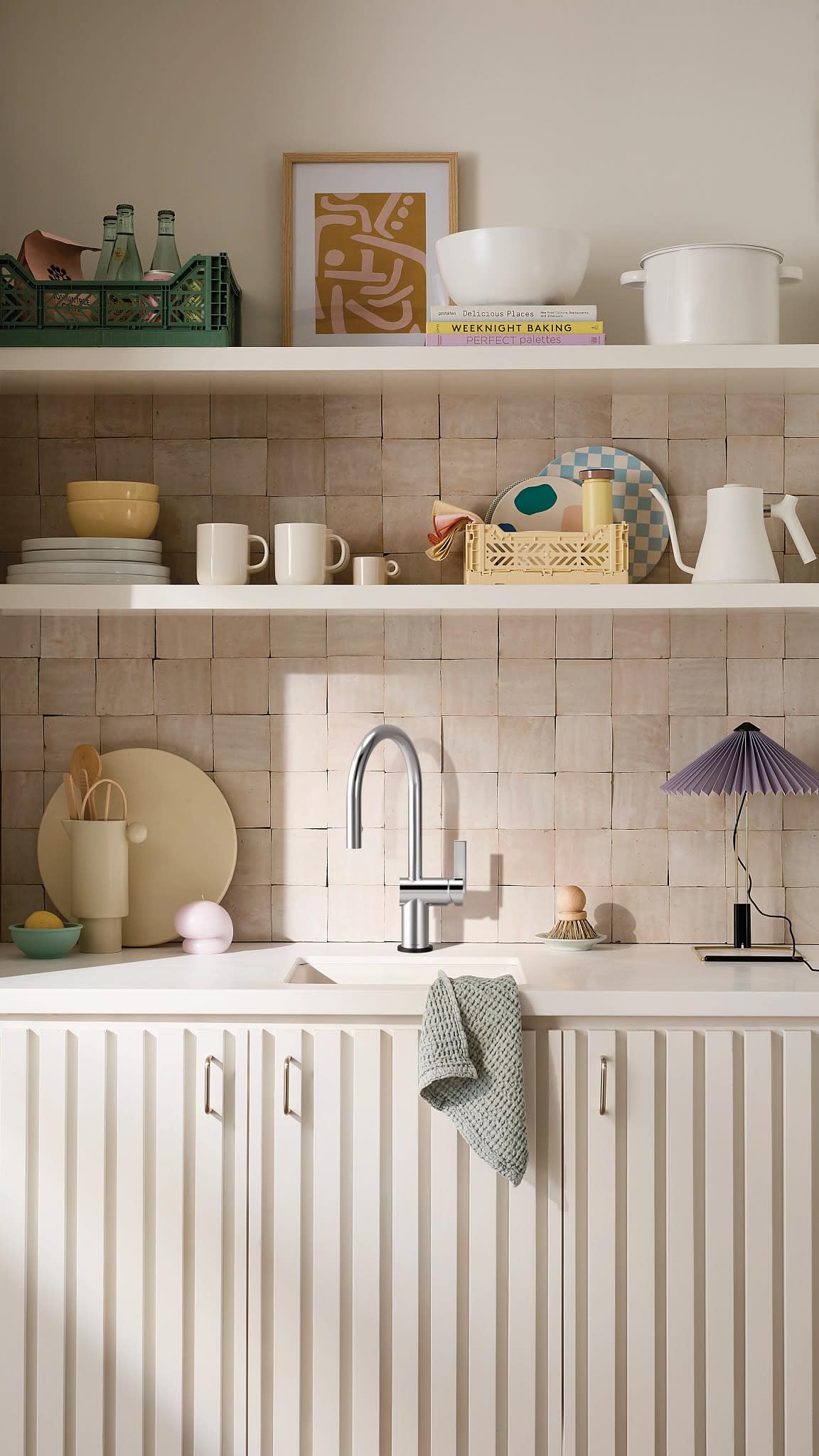 Chrome pulldown kitchen faucet with curved spout and single handle mounted above white sink in tiled kitchen.