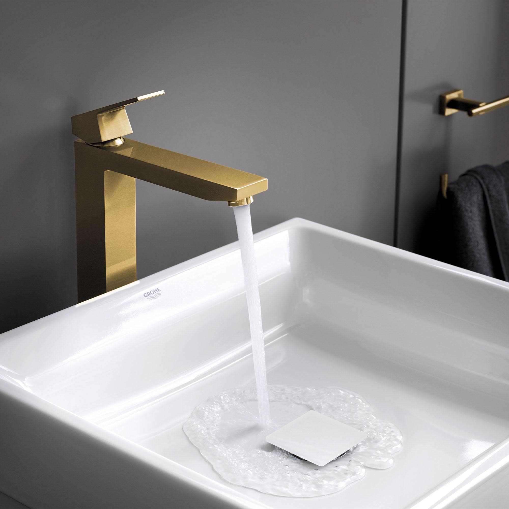 Matte black single-handle faucet with rectangular spout installed on white vessel sink with water running.
