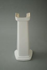White ceramic bathroom sink pedestal with rectangular upper basin, curved support arms, and wide base.