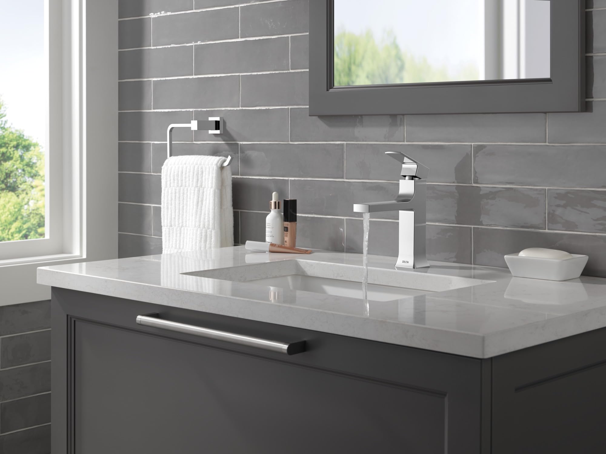 Chrome single-handle bathroom faucet with squared spout installed on white countertop sink in modern bathroom.