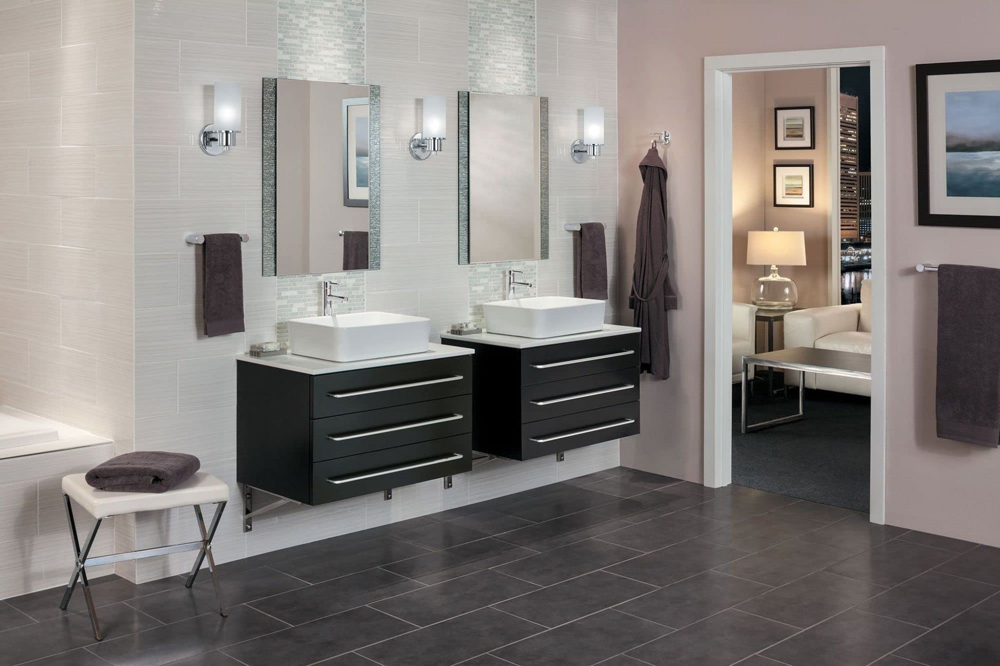 Chrome towel bar mounted on bathroom wall above dark towels in modern vanity setting.