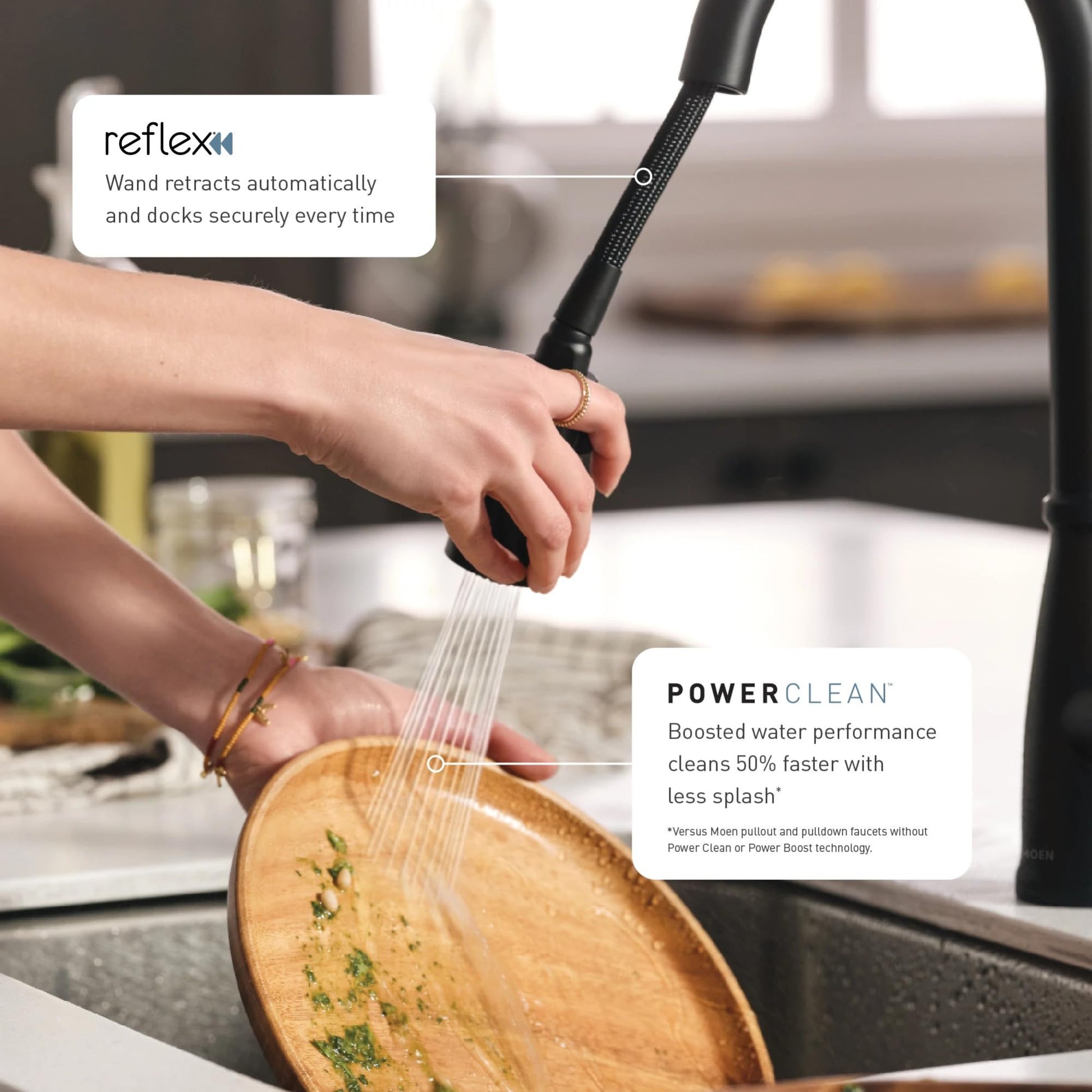 Matte black pulldown kitchen faucet with touchless wave sensor held over wooden bowl in sink.