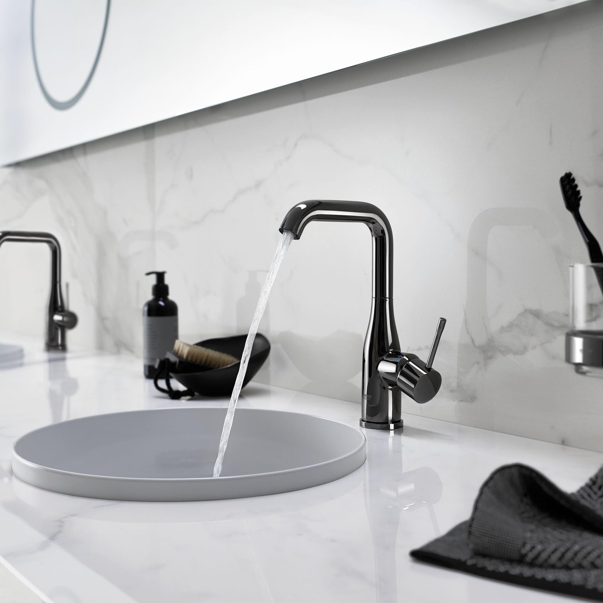 Dark graphite single-handle bathroom faucet with curved spout dispensing water into round sink basin.