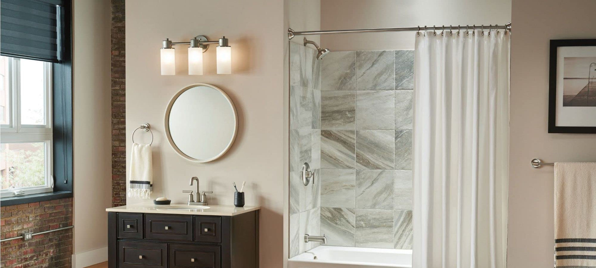 Brushed nickel wall-mounted towel ring installed on bathroom wall beside vanity mirror.