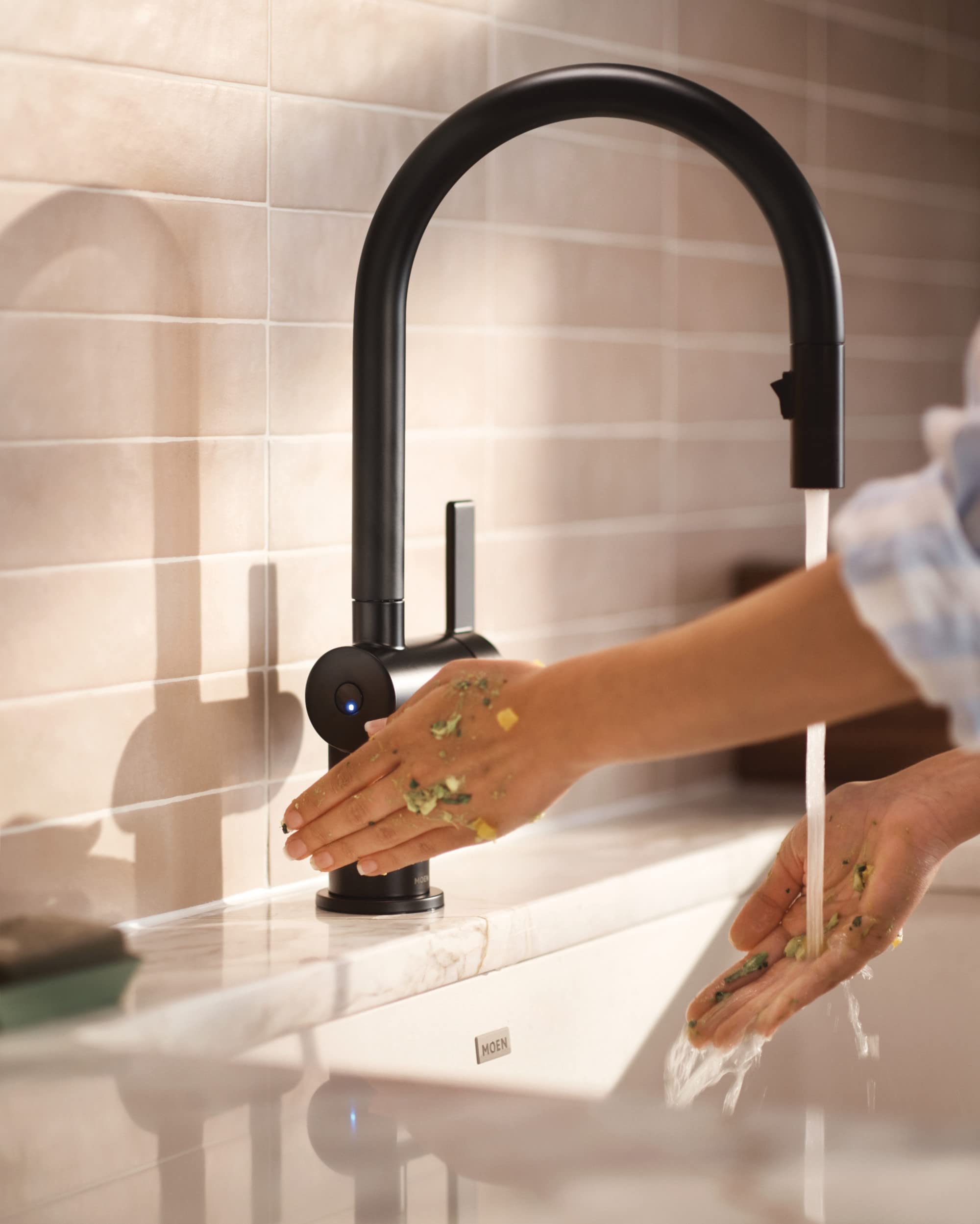 Matte black pulldown kitchen faucet with high arched spout and sensor activation shown dispensing water over sink.
