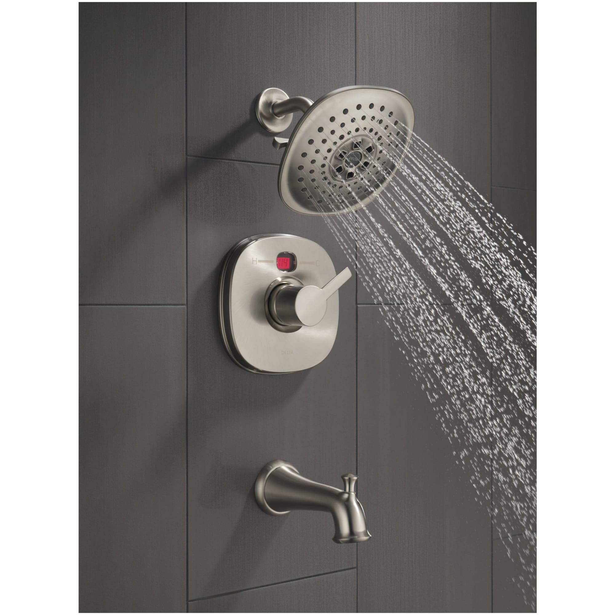 Polished nickel shower system with round showerhead, control valve, and tub spout mounted on gray tile wall.