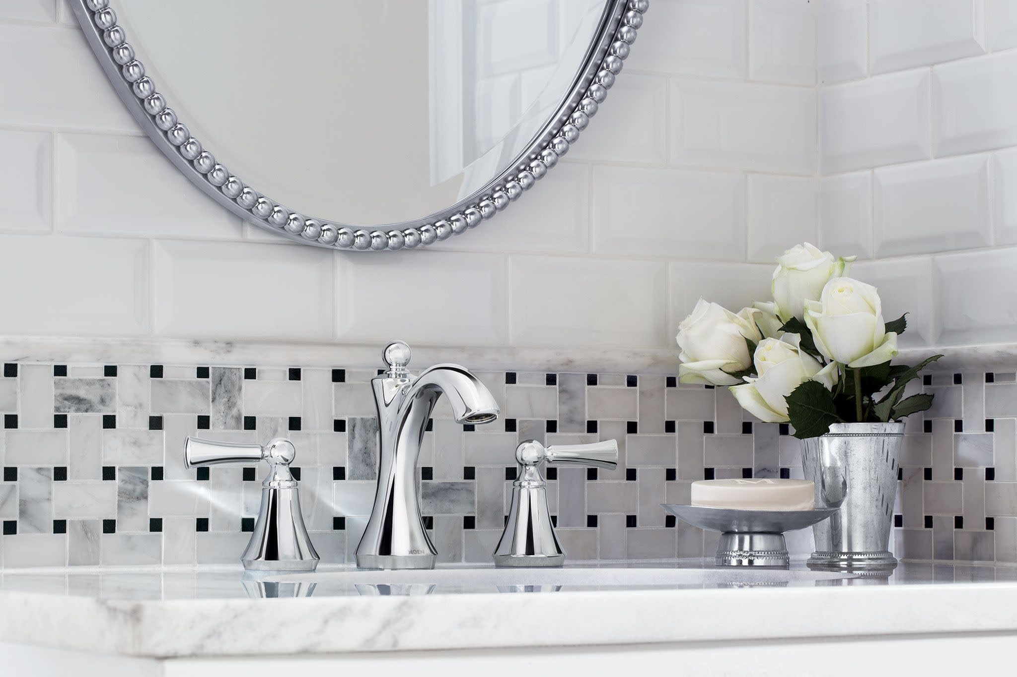Chrome two-handle widespread bathroom faucet with high arc spout and lever handles installed on marble countertop.
