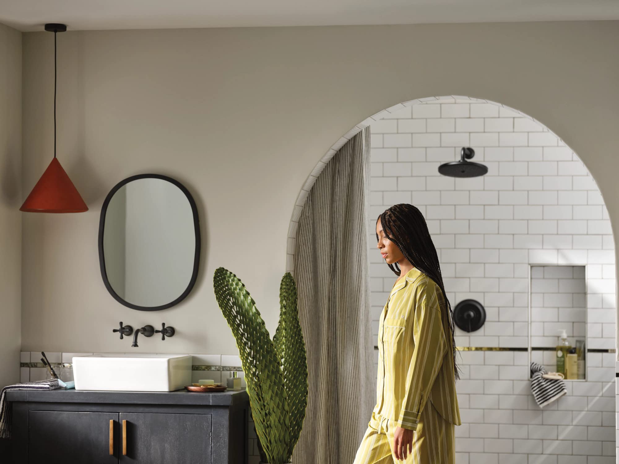 Matte black single-handle shower trim kit with round escutcheon and wall-mounted controls installed in white subway tile bath