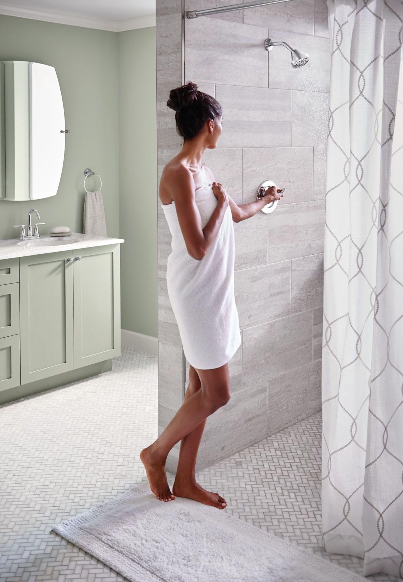 Chrome single-handle shower trim kit installed on tile shower wall with showerhead and control valve visible.