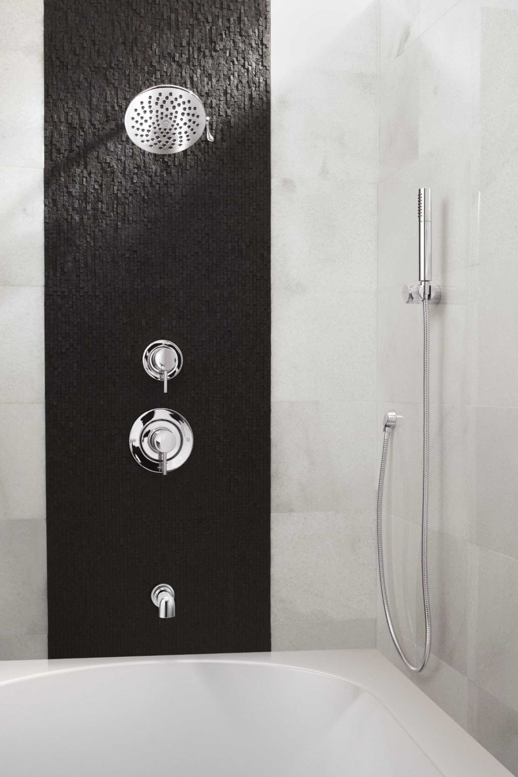 Chrome handheld shower with hose and holder mounted on black tile wall next to rainfall showerhead and control valves.