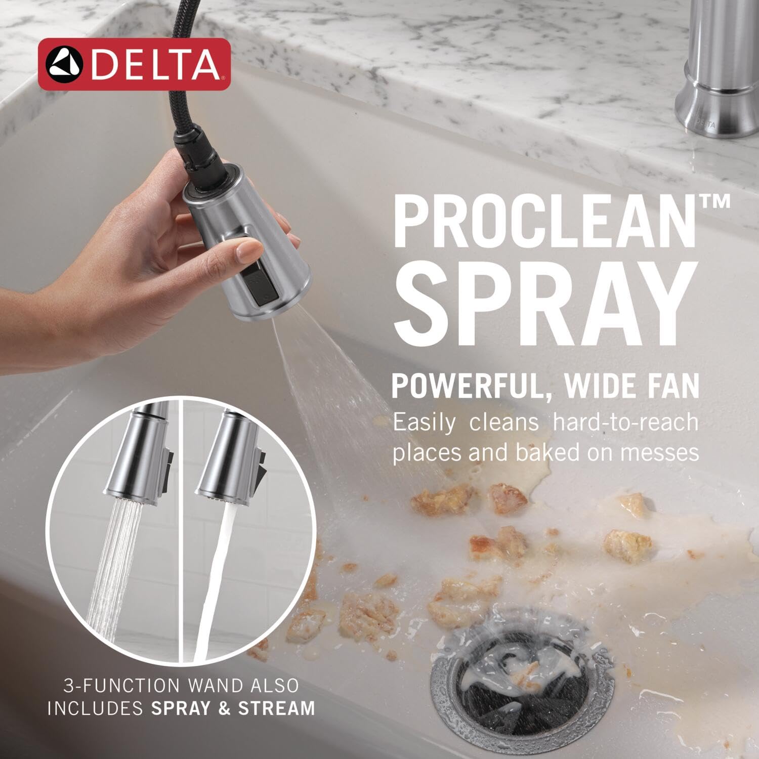 Chrome pull-down kitchen faucet with spray wand being held over sink with water running and food debris visible.
