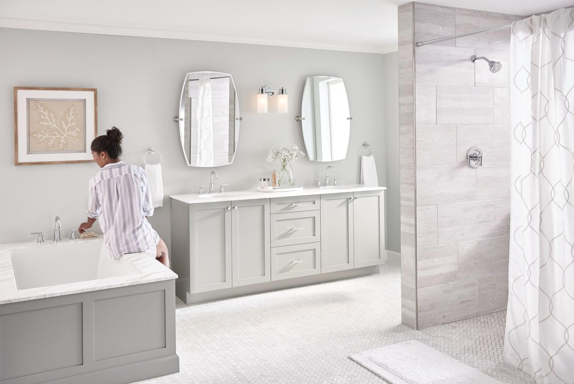 Chrome two-handle deck-mounted roman tub faucet installed on white bathtub in modern bathroom.
