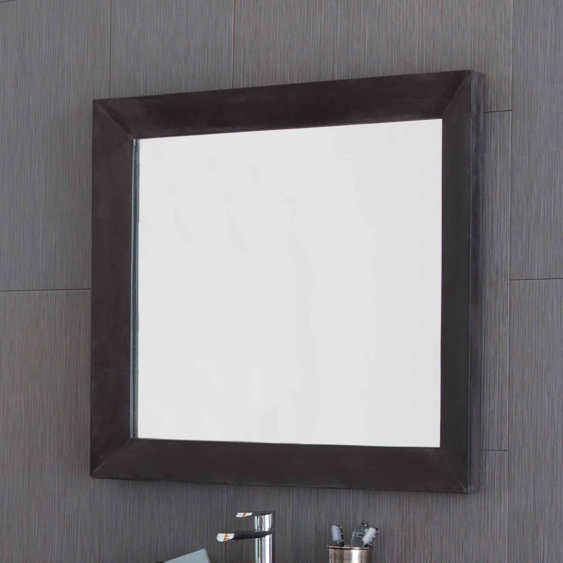 Large rectangular mirror with dark frame mounted on gray tile wall above bathroom vanity.