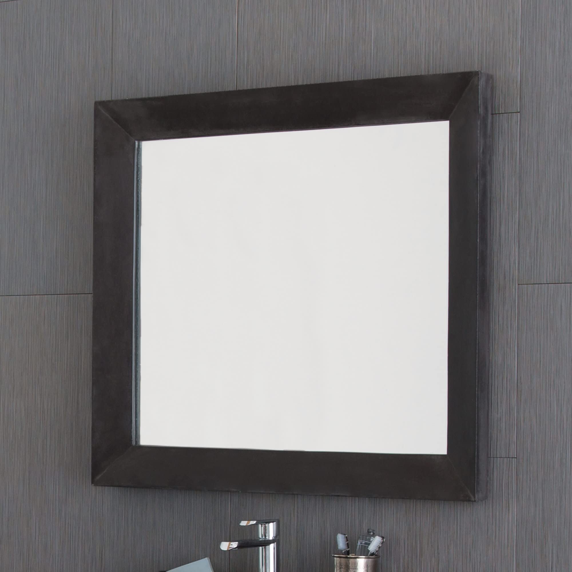 Large rectangular mirror with dark frame mounted on gray tile wall above bathroom vanity.