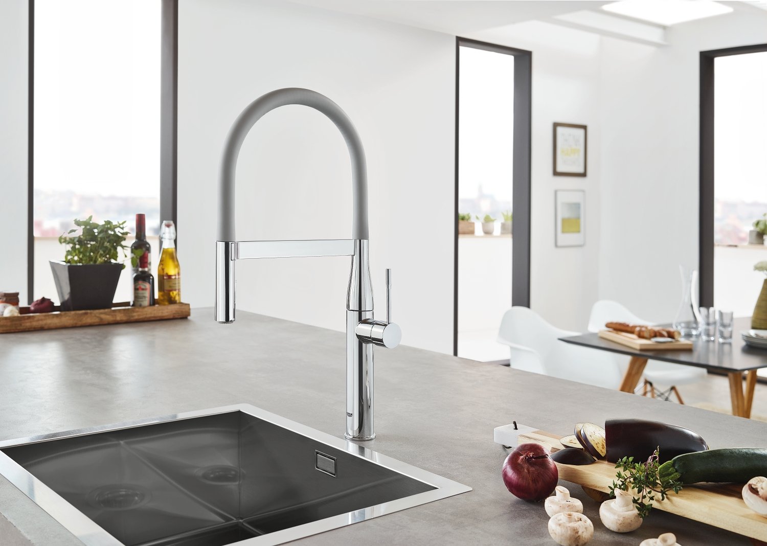 Matte dark grey kitchen faucet with curved arch spout and pull-down hose over undermount sink.