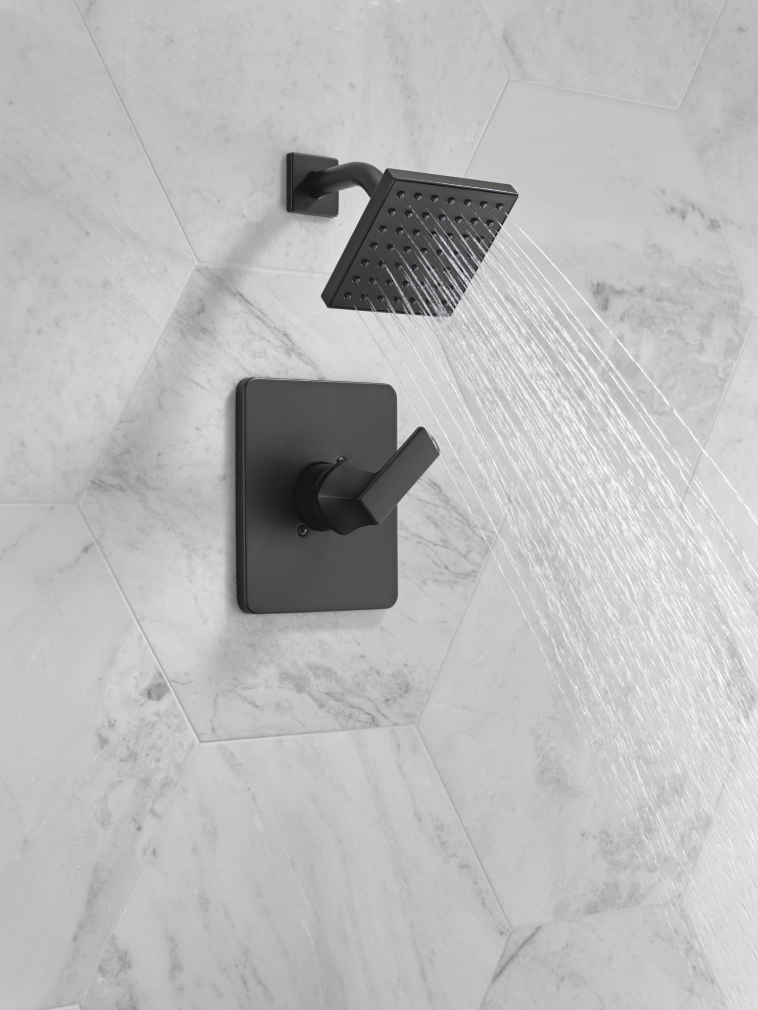 Matte black shower trim with square valve control and rainfall showerhead mounted on marble tile wall.