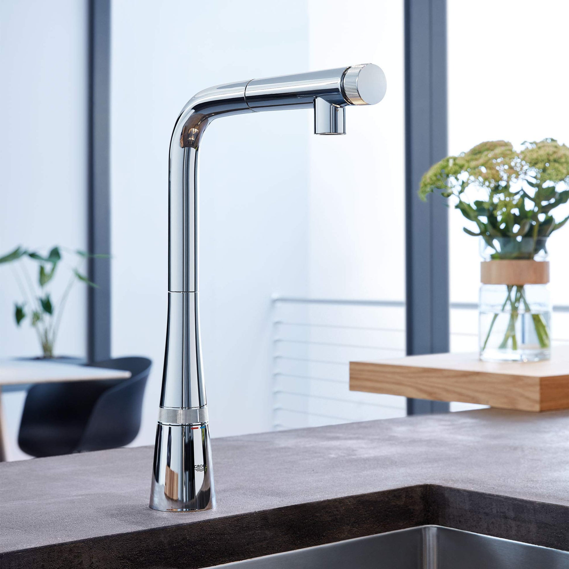 Chrome pull-out kitchen faucet with tall curved spout and control handle mounted above sink.