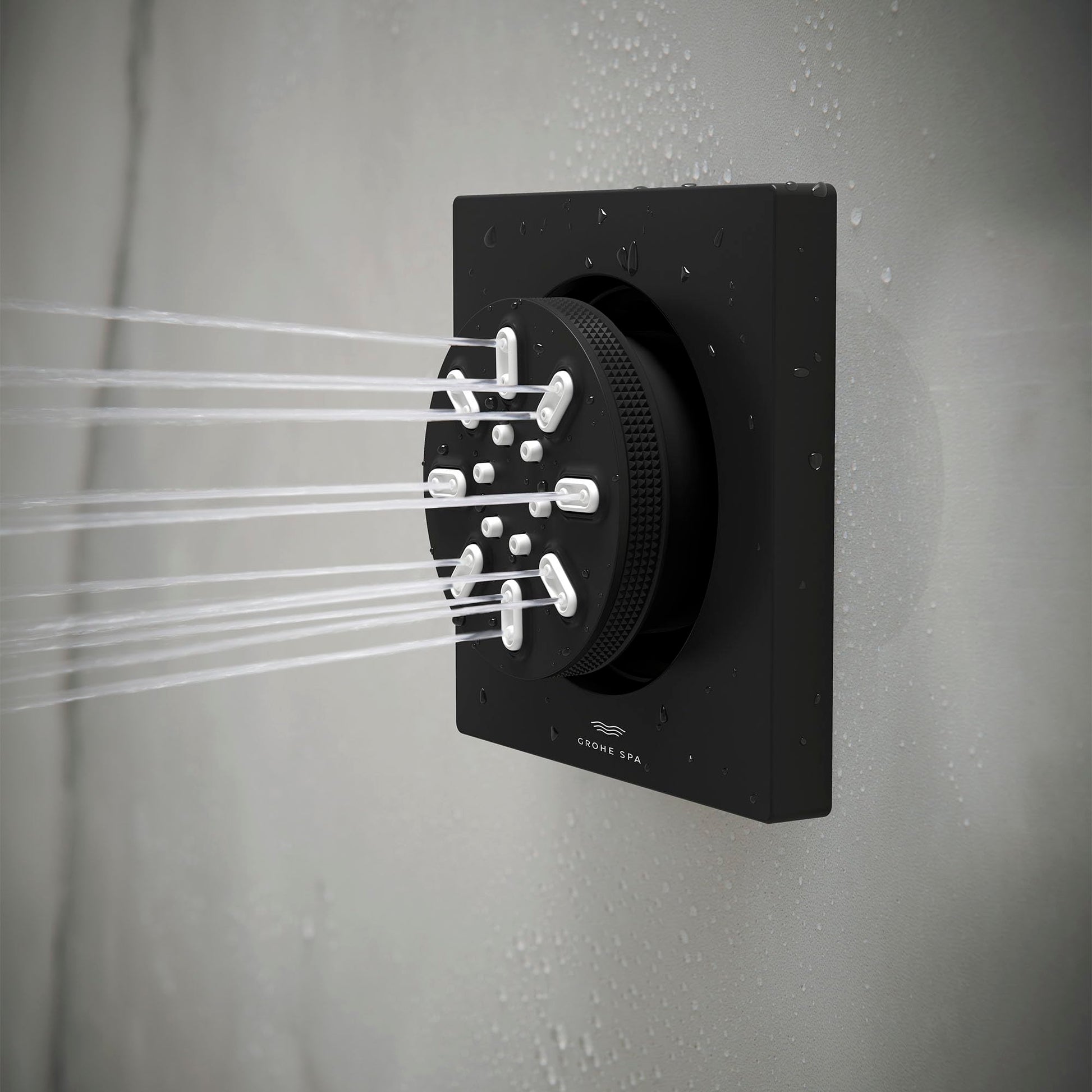 Matte black square body spray mounted on wall with water spraying from multiple nozzles.