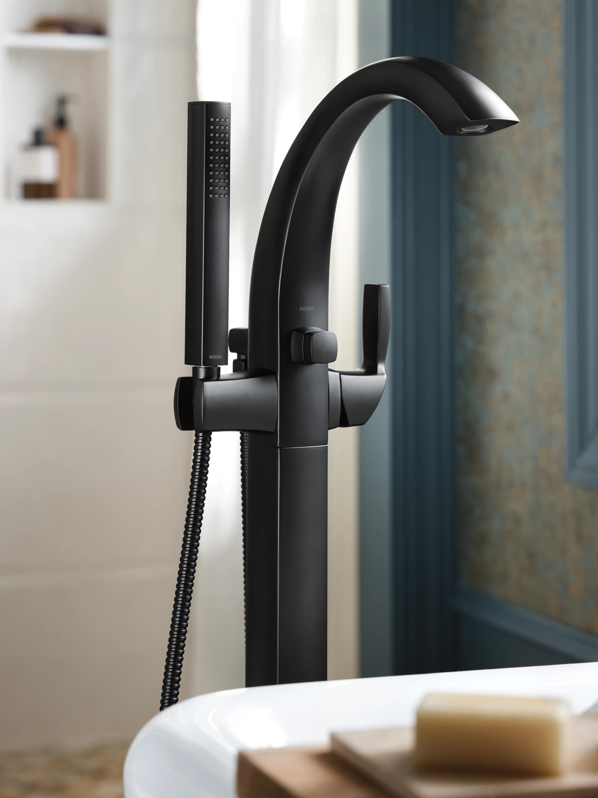 Matte black freestanding tub filler with curved spout, single handle, and detachable handheld showerhead.