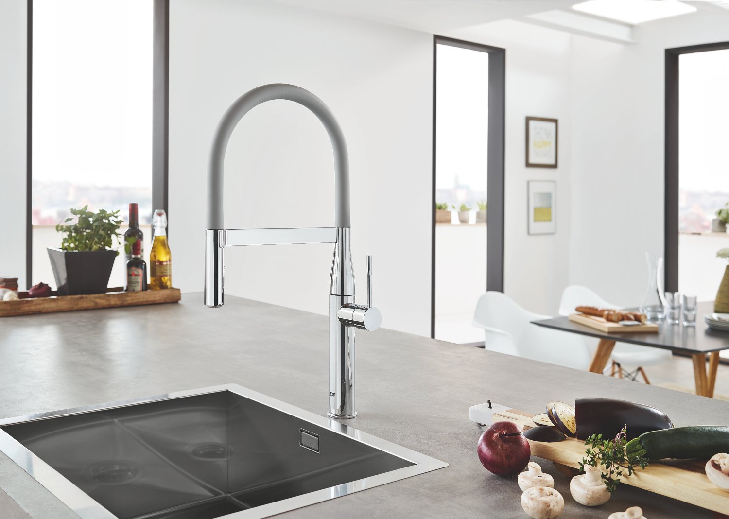 Matte dark grey kitchen faucet with curved arched spout and pull-down hose, installed above sink in modern kitchen.