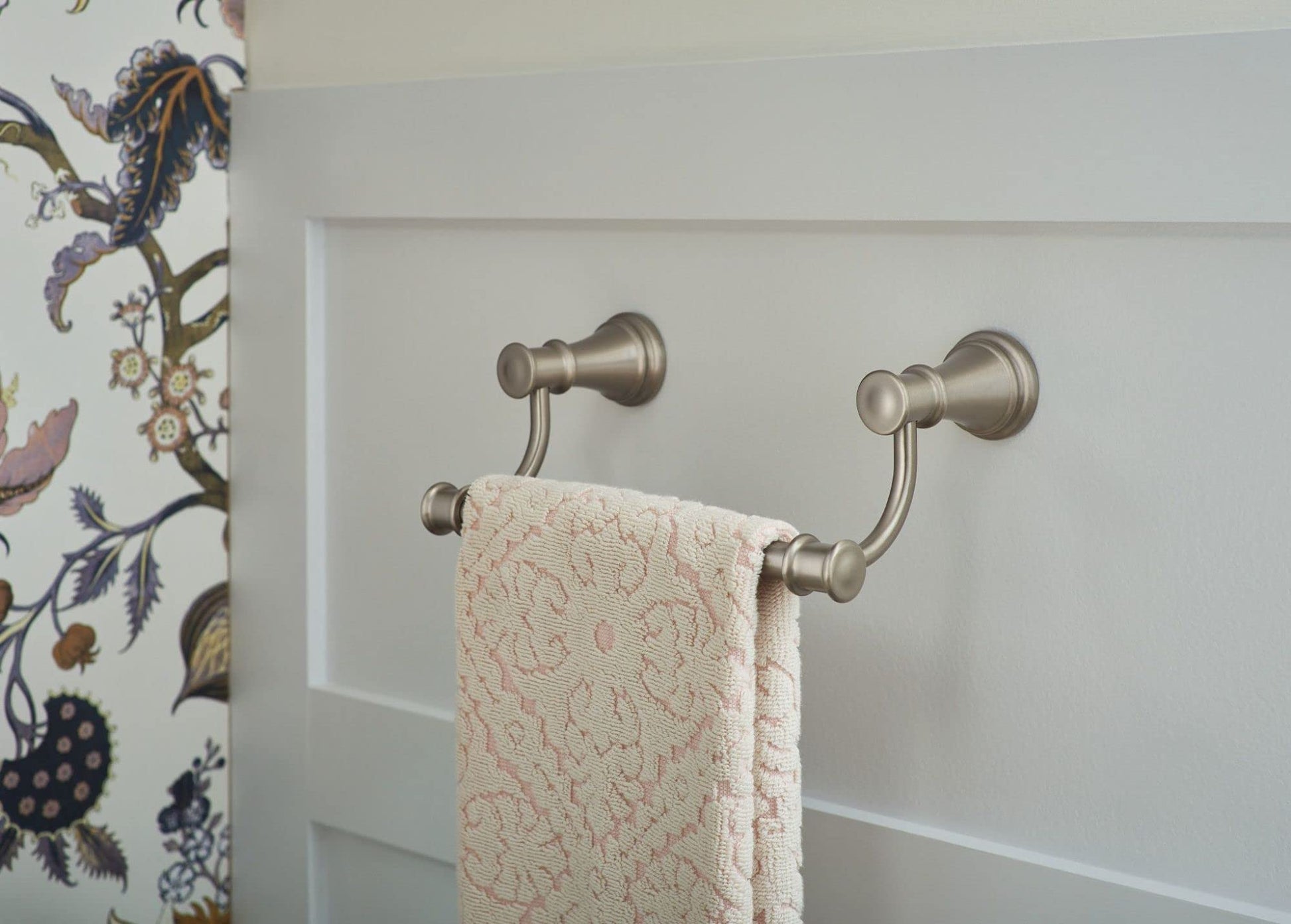 Brushed nickel double towel ring mounted on white wall with cream towel draped across both rails.