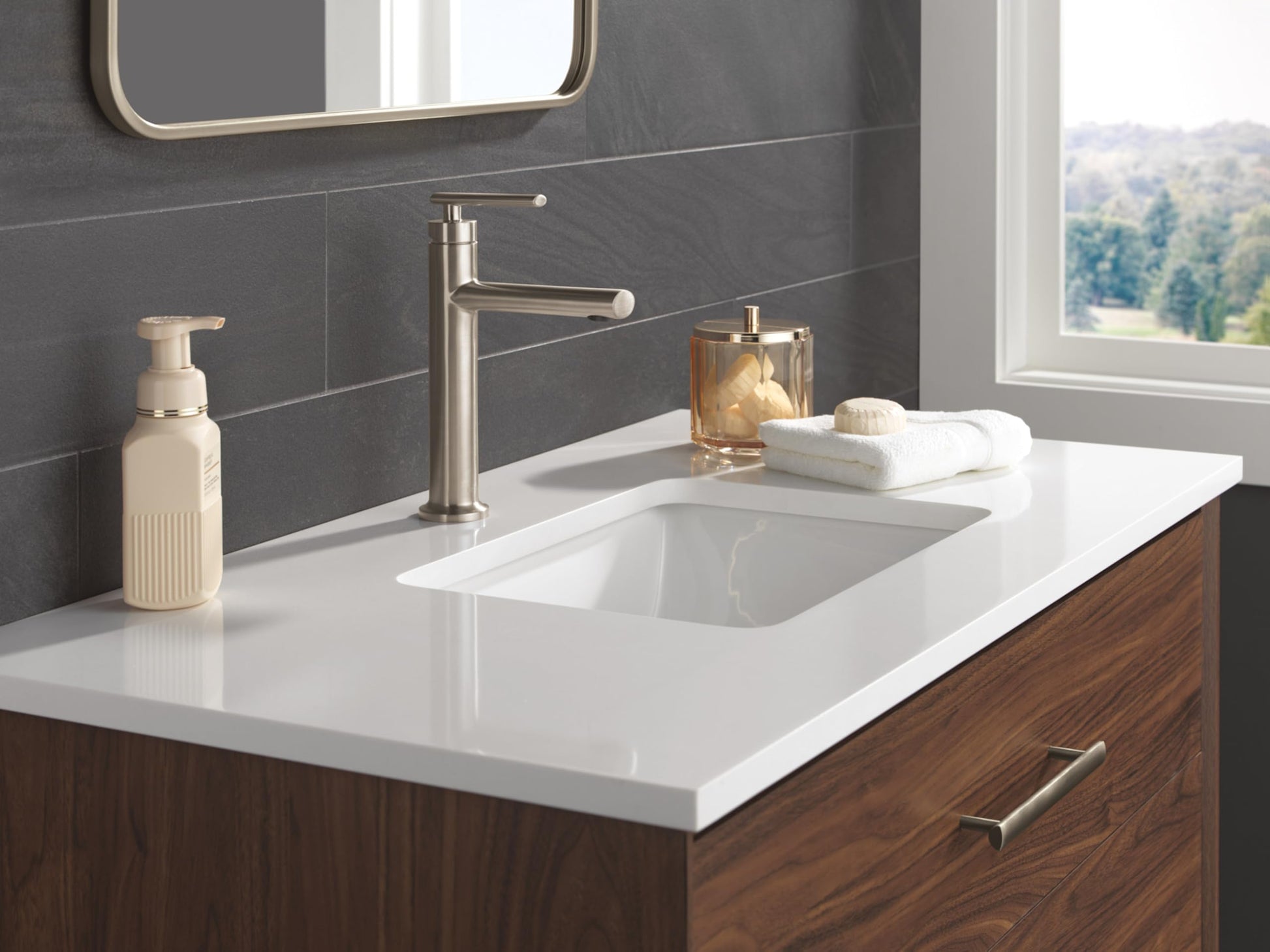 Champagne bronze single handle bathroom faucet with tall spout installed on white countertop above rectangular sink.