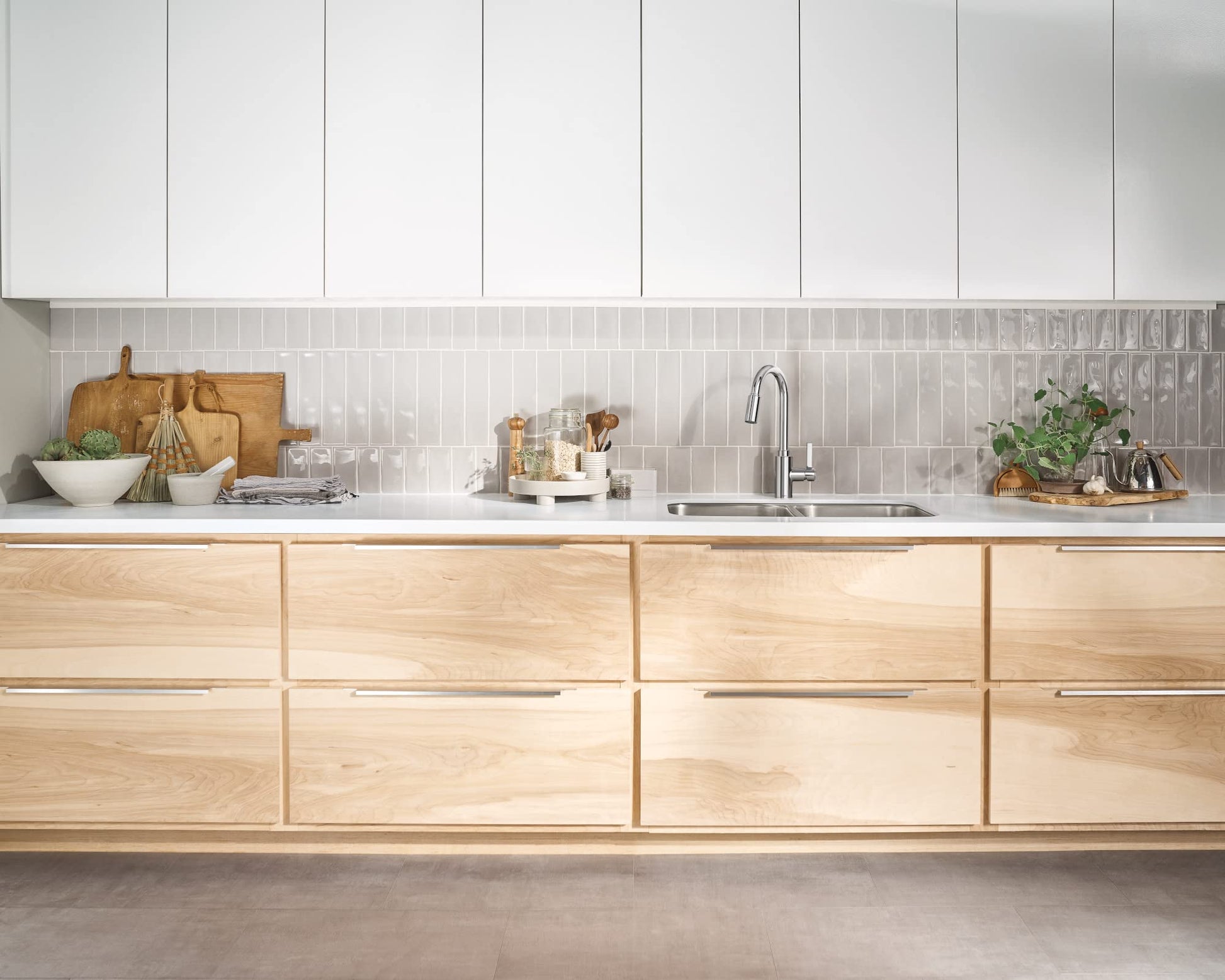 Chrome single-handle kitchen faucet with pull-down sprayer mounted above sink in modern kitchen.