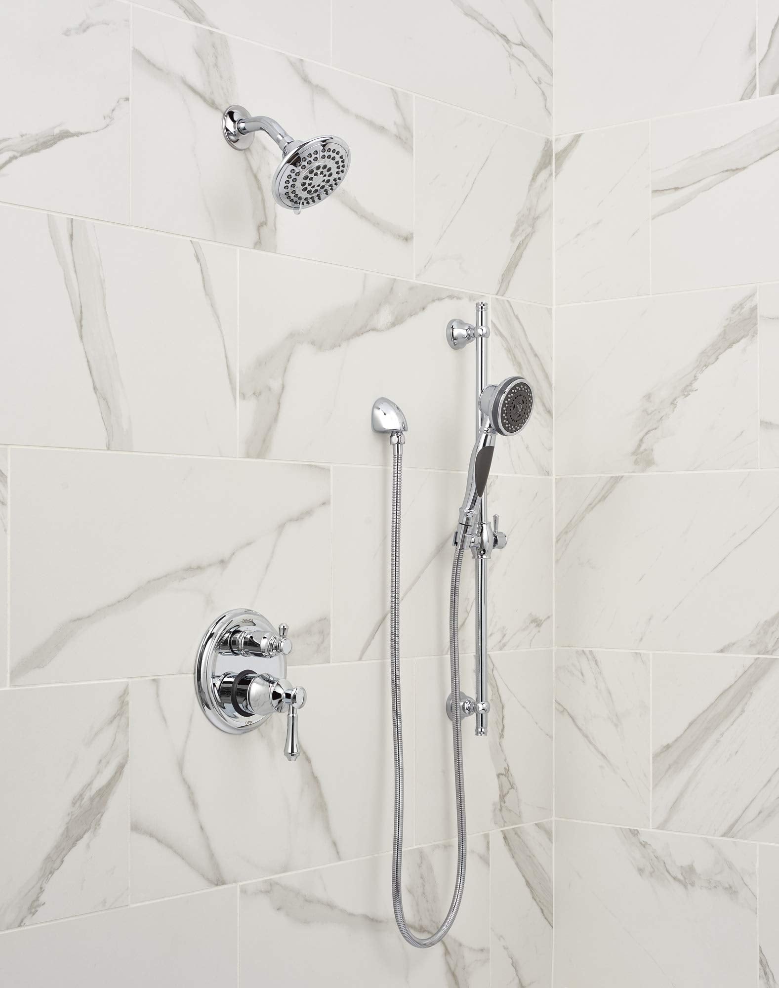 Chrome shower system with fixed showerhead, handheld spray, and valve trim mounted on marble tile wall.