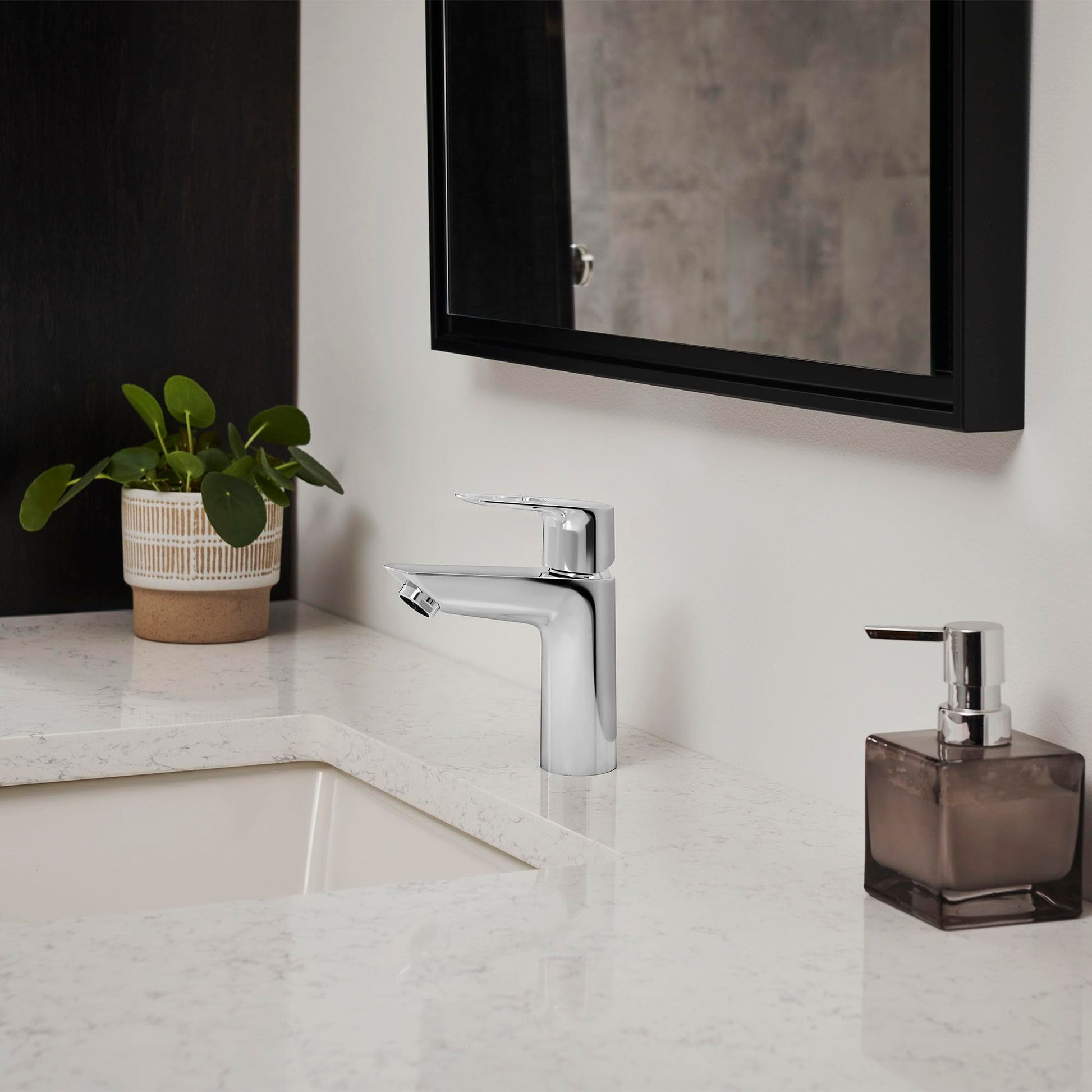Chrome single-handle bathroom faucet with pull-out sprayer mounted on white marble countertop.