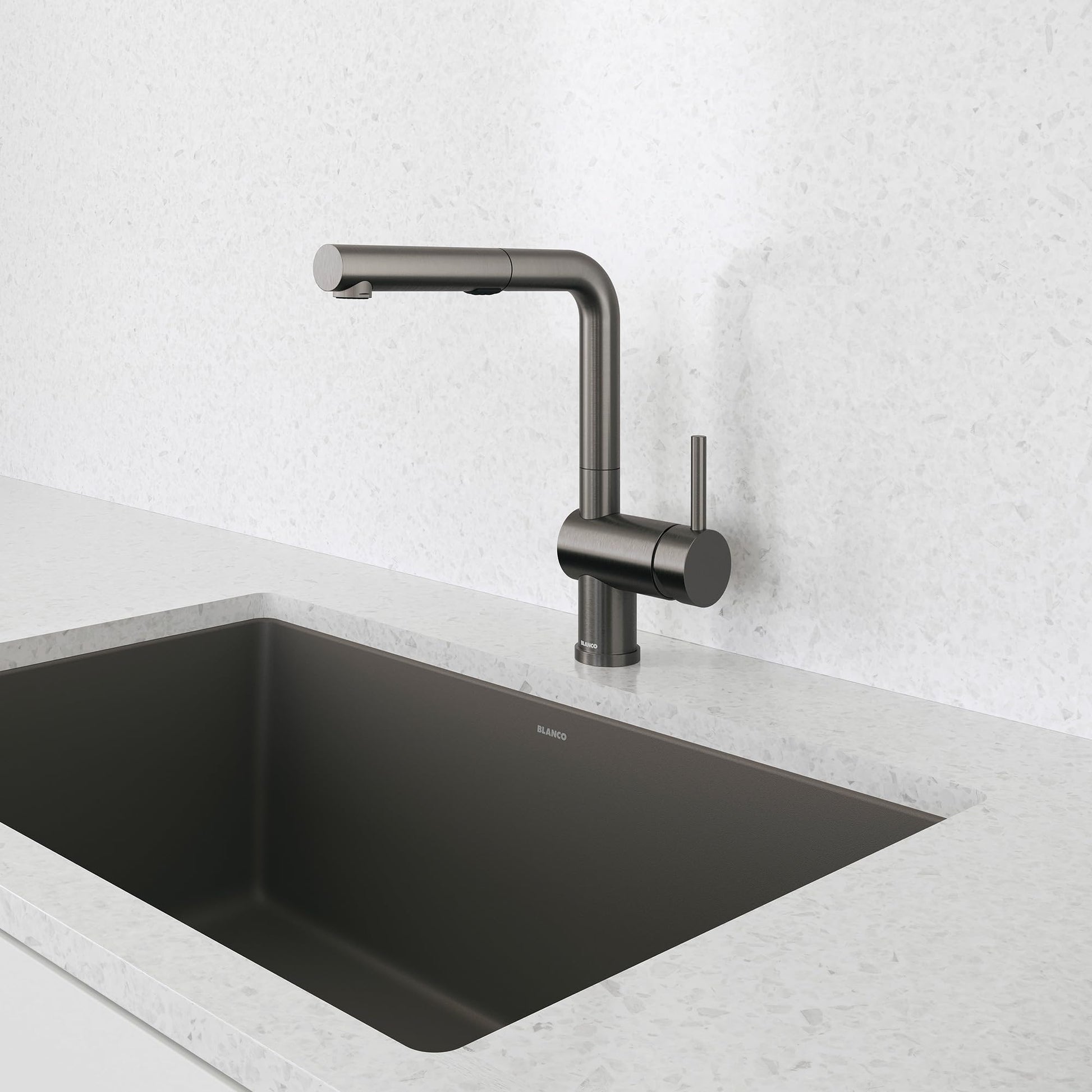 Dark steel pull-out kitchen faucet with angular spout mounted above black sink basin.