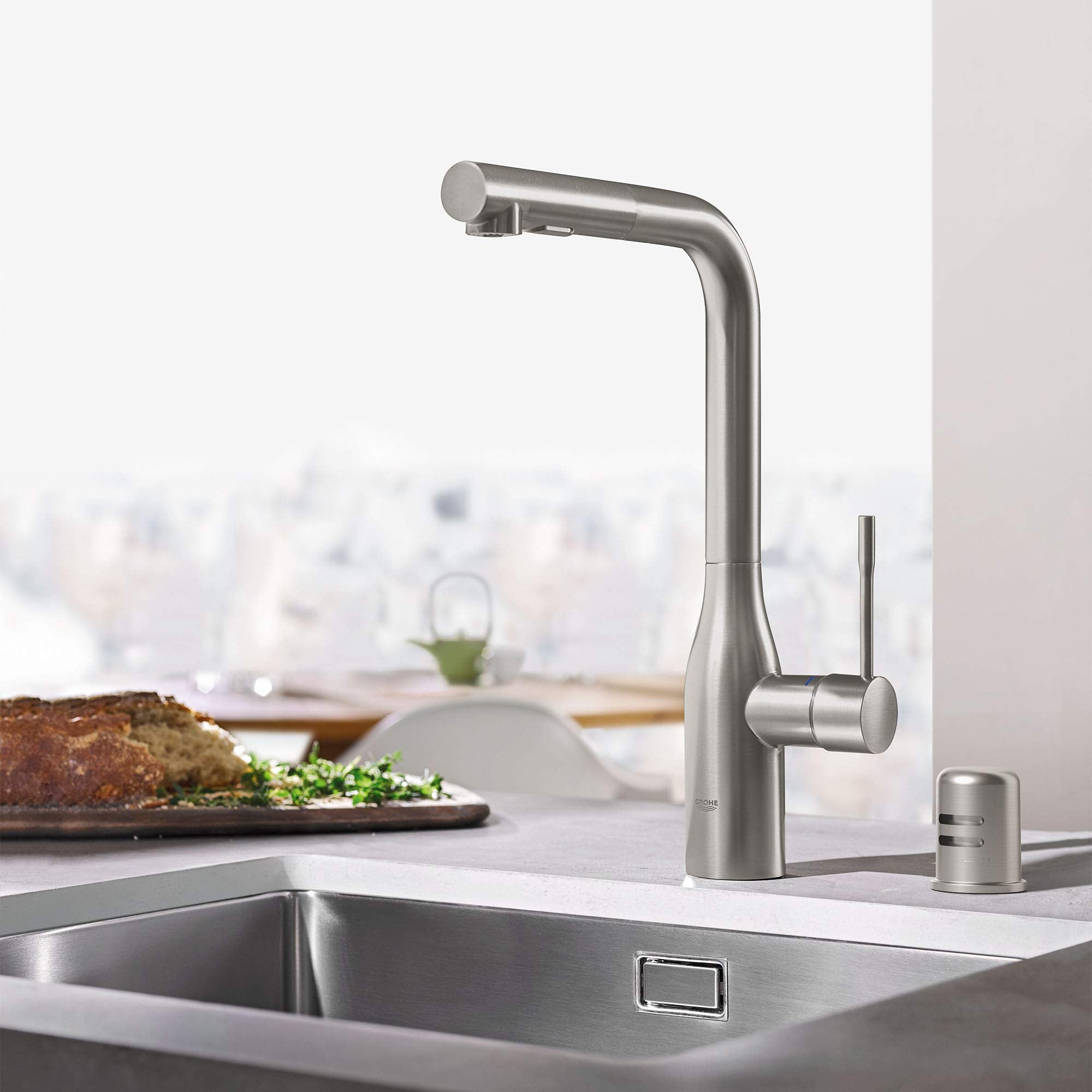 Grohe Supersteel air gap component with cylindrical nozzle and small metal cap shown installed on kitchen sink faucet.