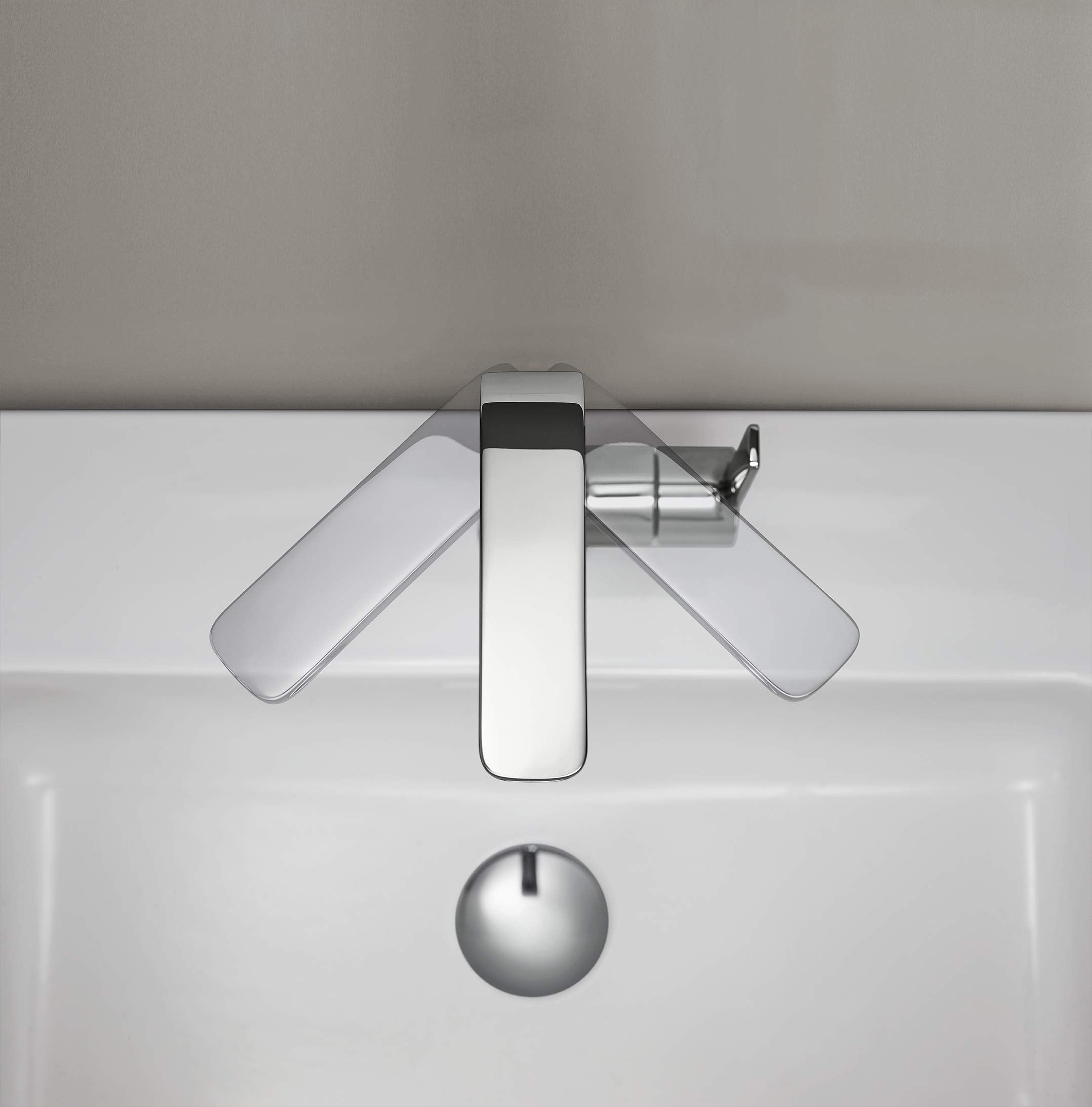 Chrome single-handle bathroom faucet with rectangular spout and two lever handles extended to sides, mounted on white sink ba