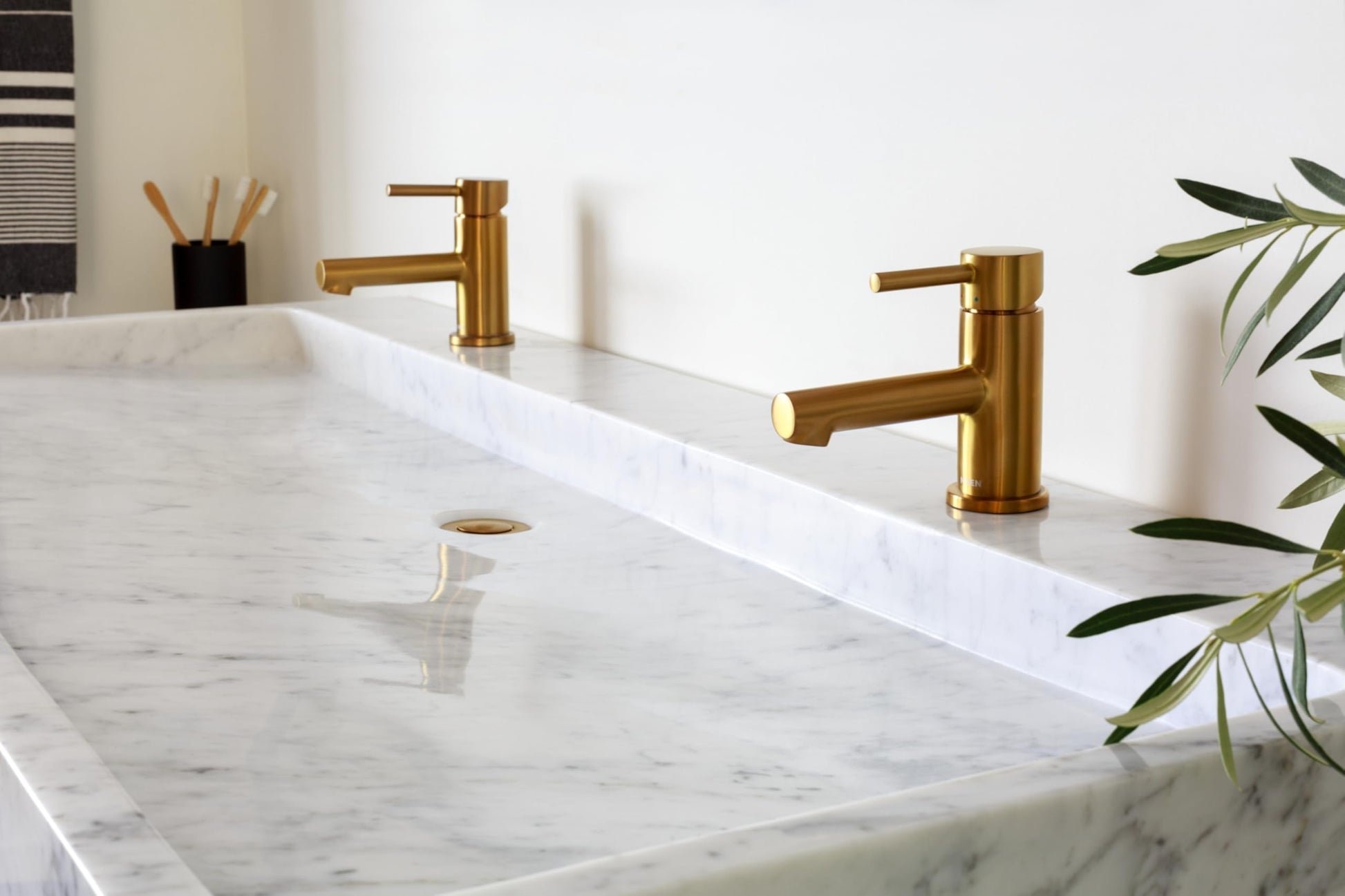 Brushed nickel single-handle low-arc bathroom faucet with lever handle mounted on white marble countertop.