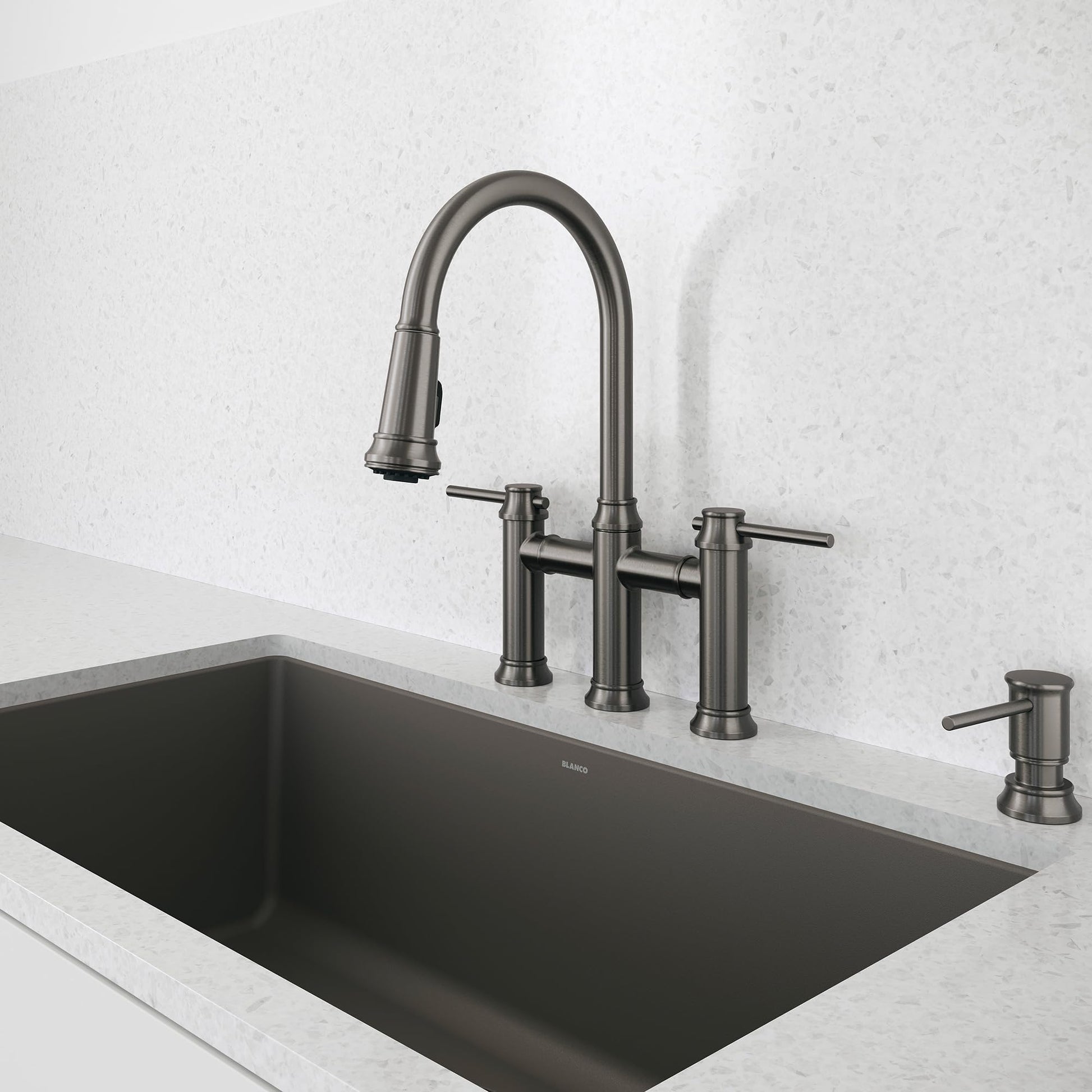 Satin dark steel bridge pull-down faucet with arched spout and dual lever handles mounted above black rectangular sink.