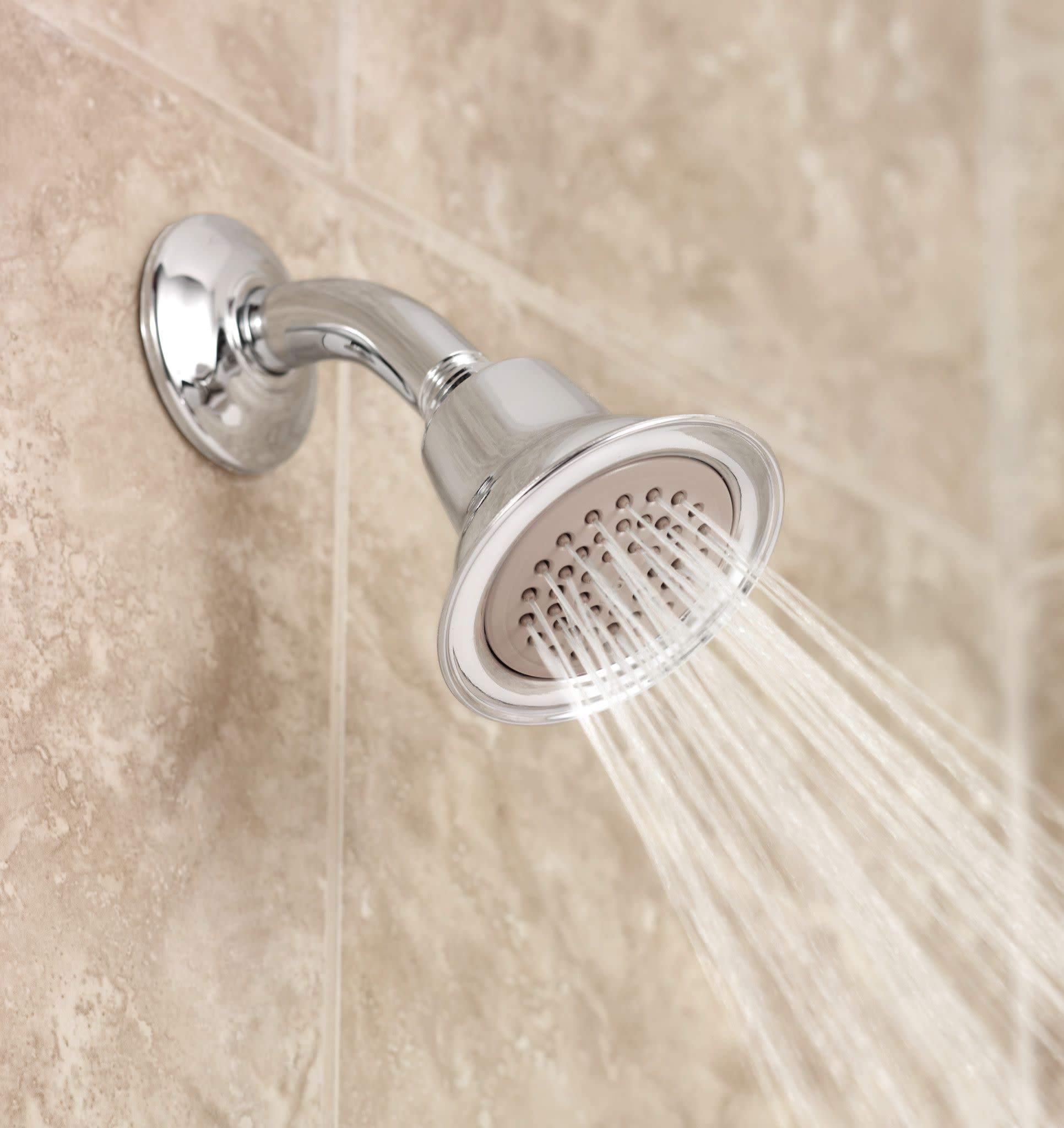 Brushed nickel shower head with circular face and perforated spray pattern mounted on angled arm against tile wall.