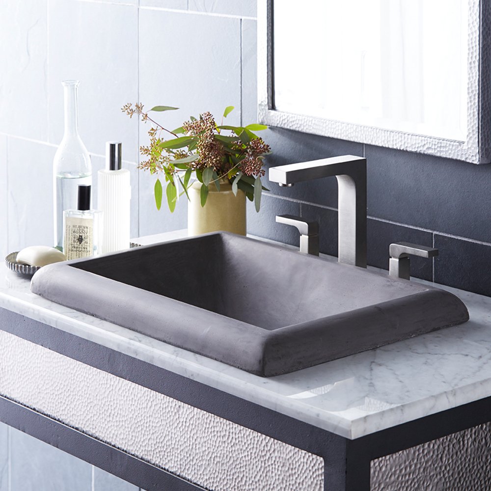 Slate-colored rectangular bathroom sink with curved rim mounted on marble countertop with chrome faucet.