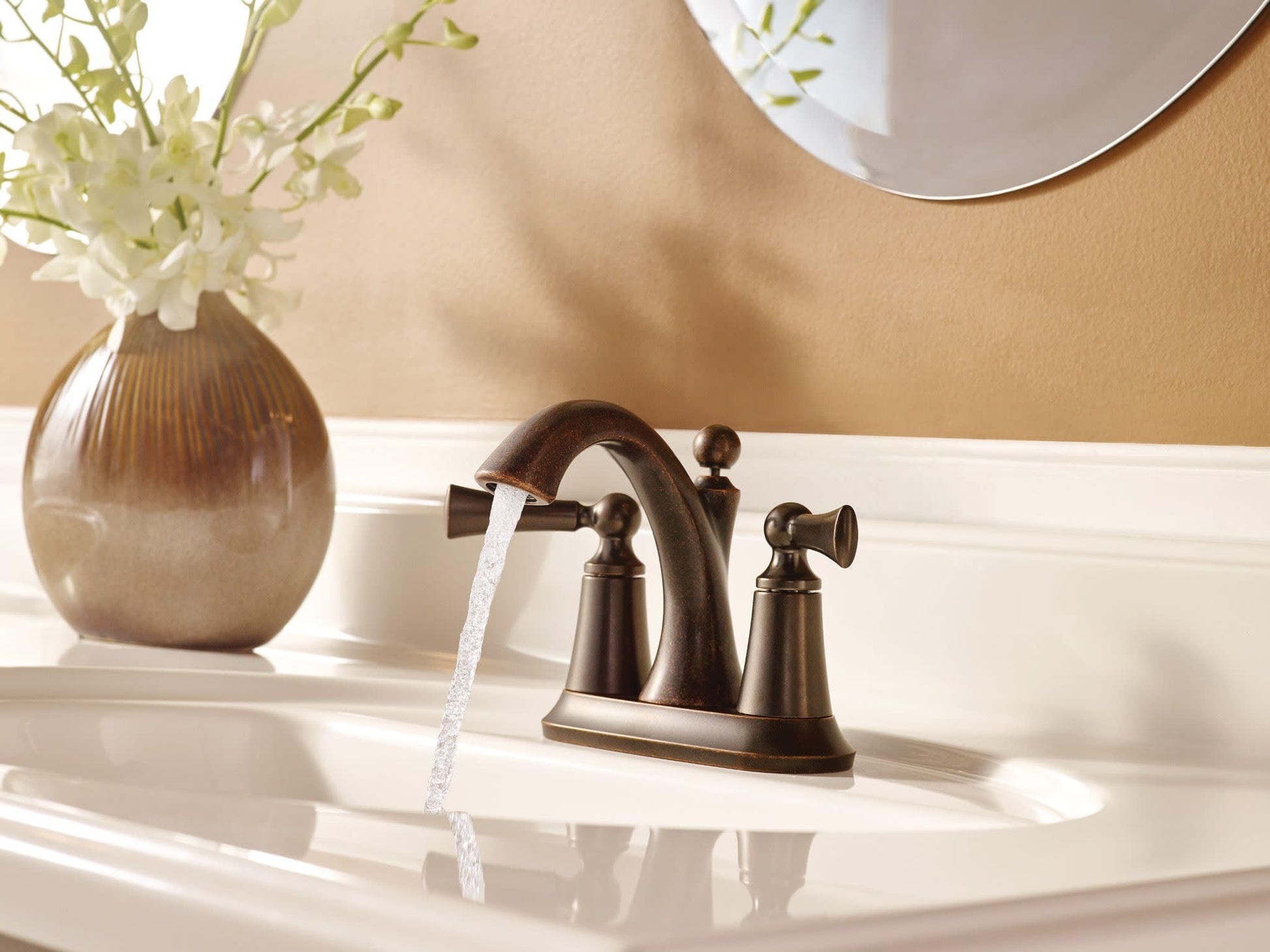 Chrome two-handle bathroom faucet with curved spout and knob handles installed on white sink basin.