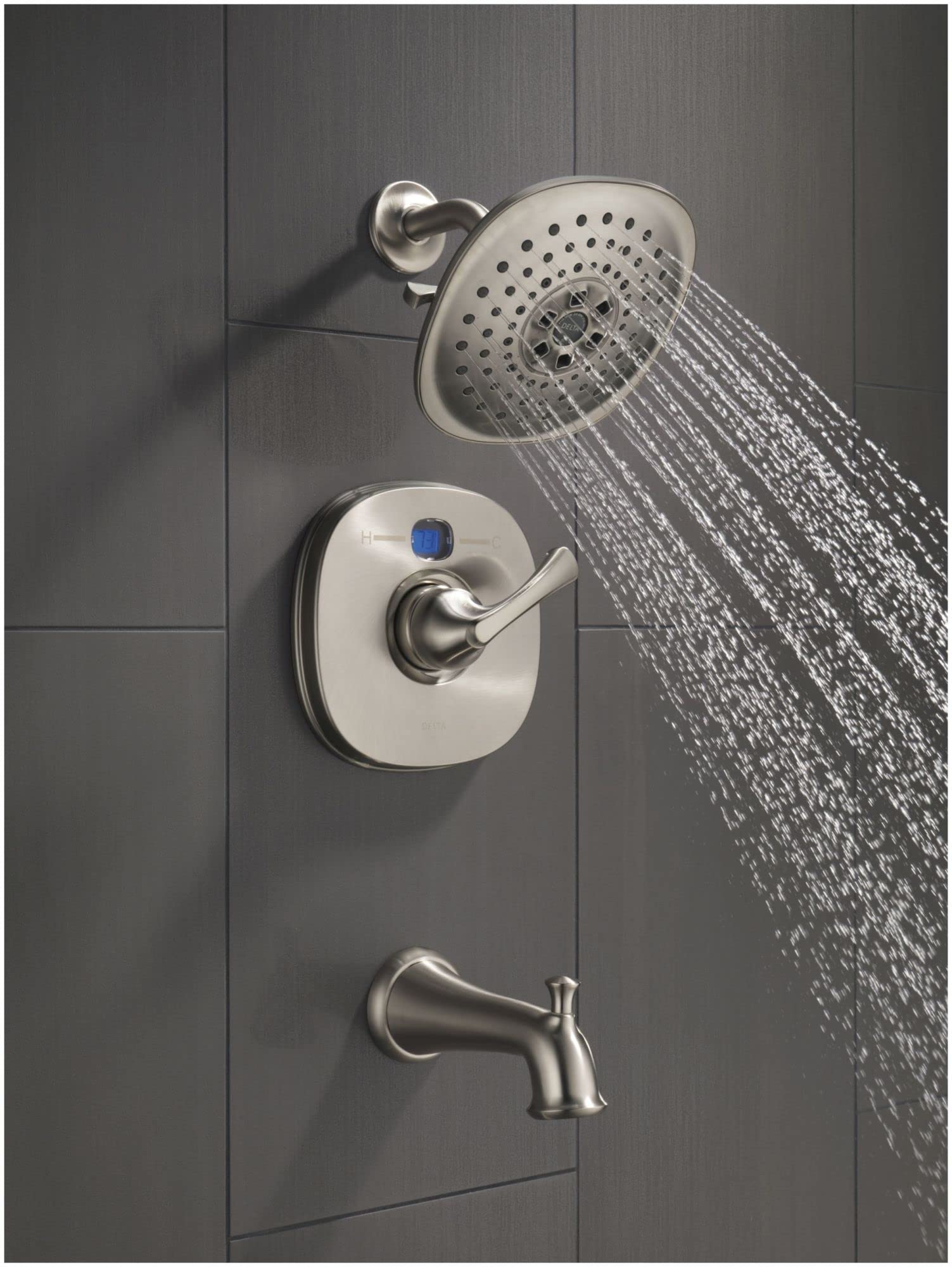 Black stainless steel shower flange with perforated head mounted on gray tile wall with control valve and tub spout.
