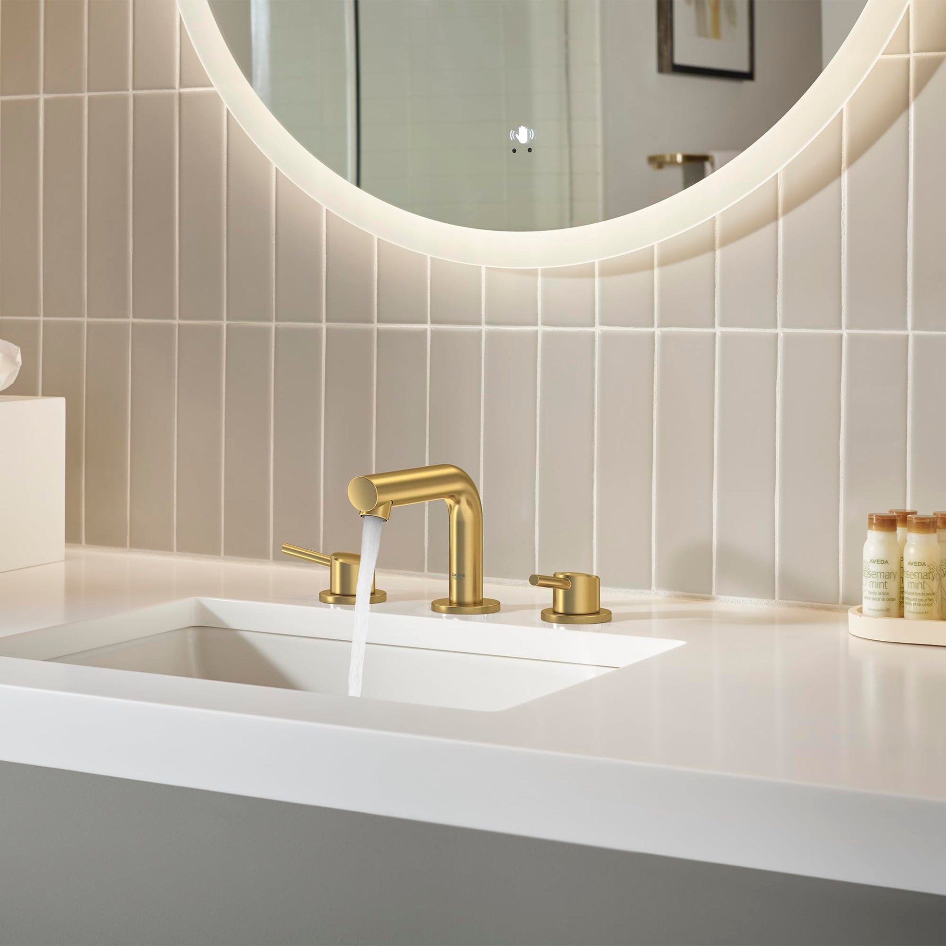 Brushed gold widespread bathroom faucet with curved spout and two round handles installed on white sink countertop.